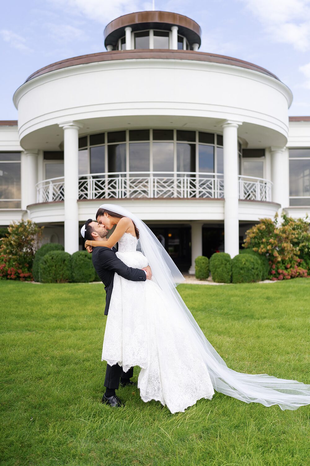 The groom lifts his bride on the great lawn in front of Glen Island's rotunda mansion.