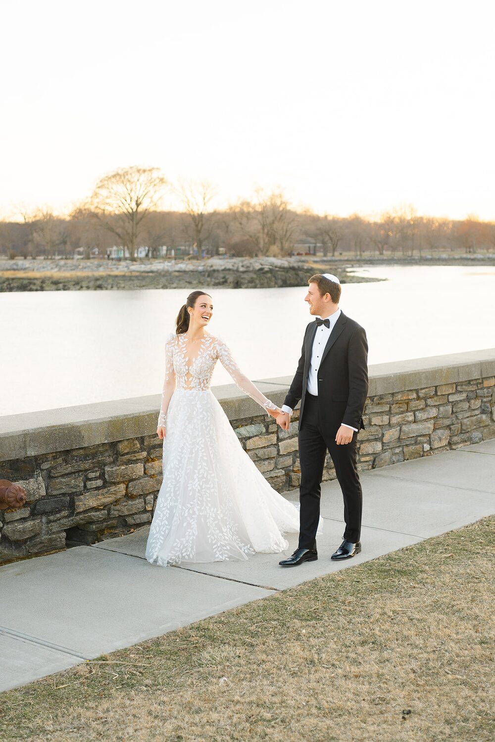 Hand in hand, the couple strolls the pond-side stone wall.