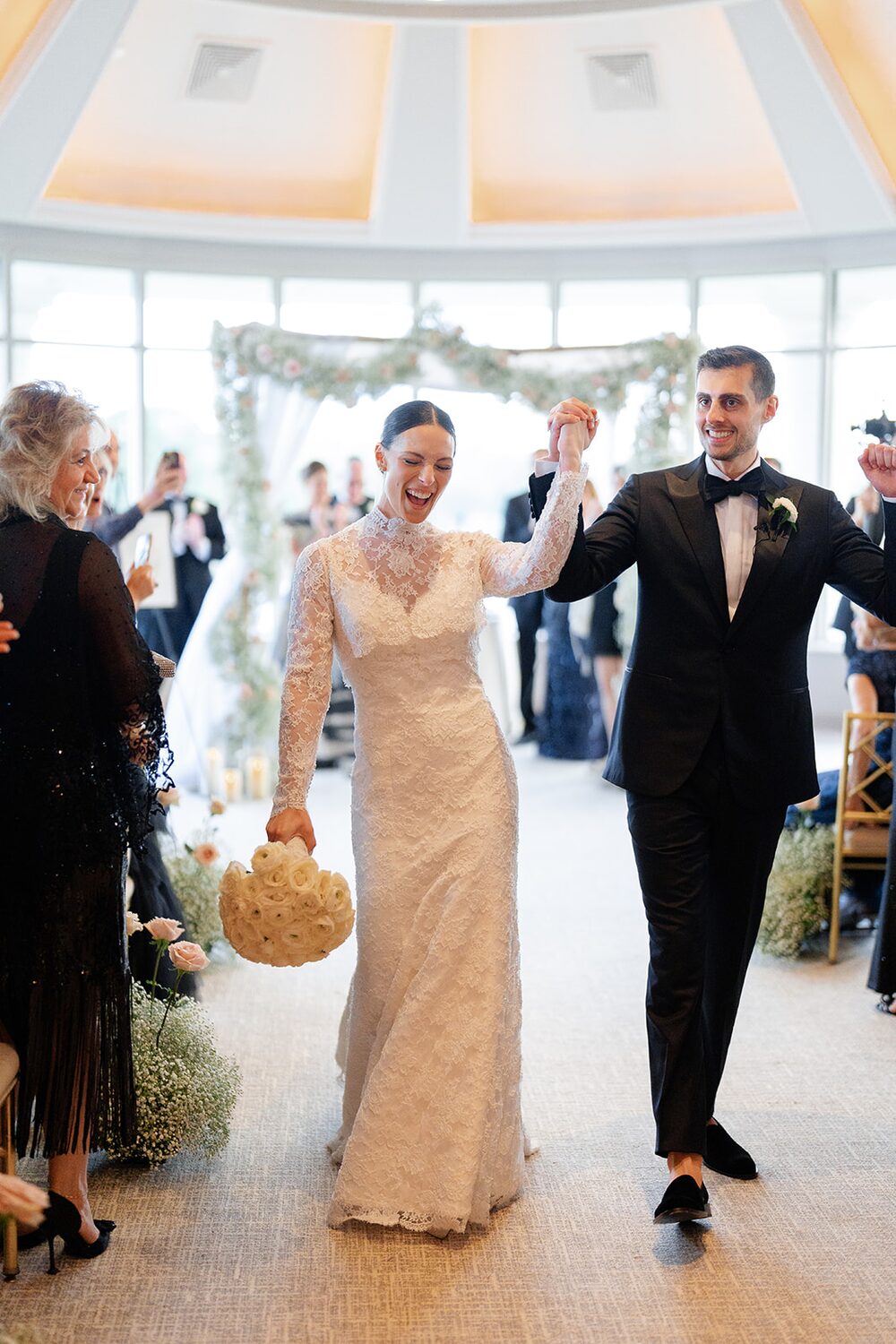 The bride swings her baby's breath pomander as the newlyweds dance back up the aisle.