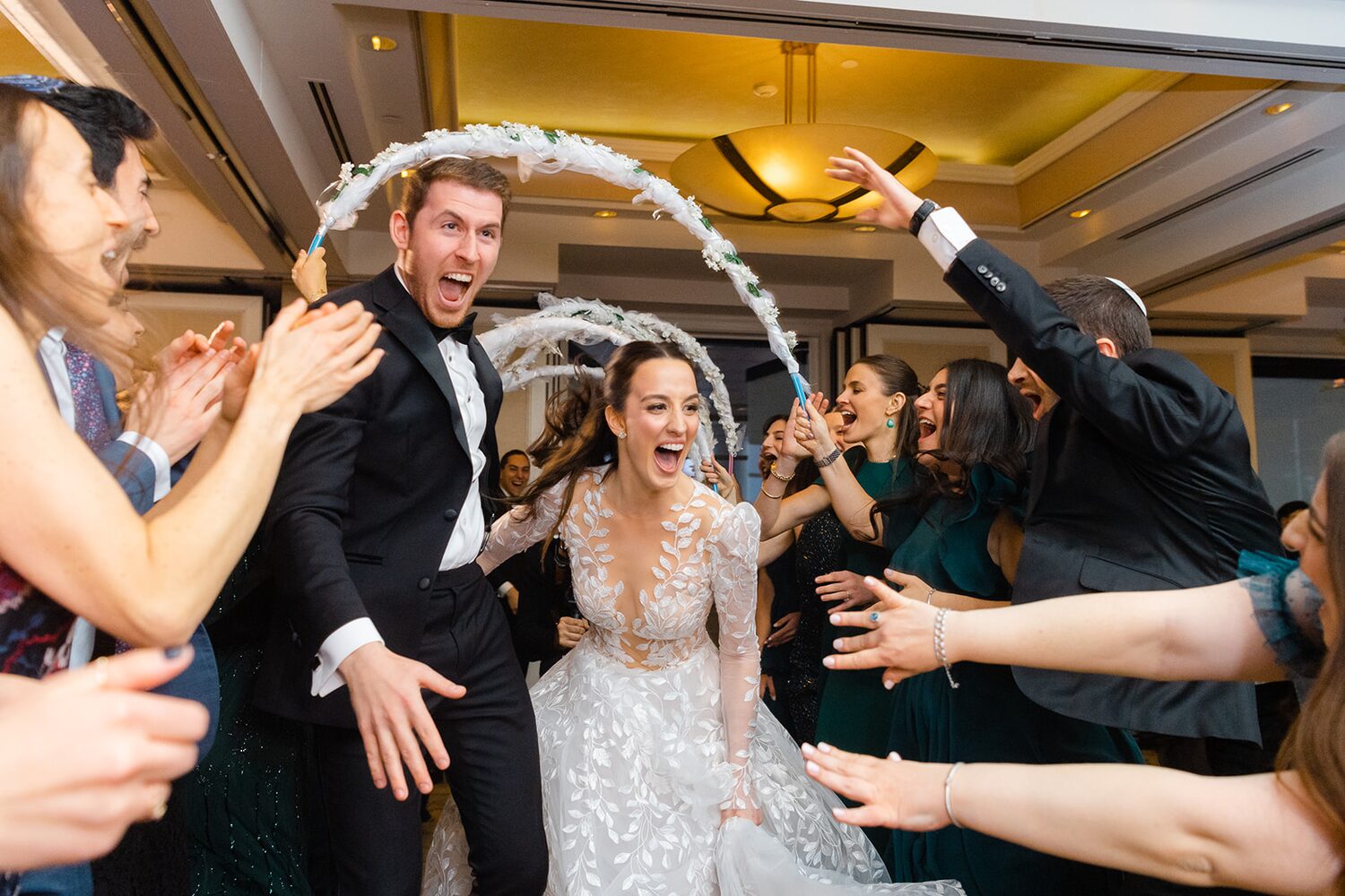 Friends raise a streamer arch over the laughing couple during the first dance set's shtick.