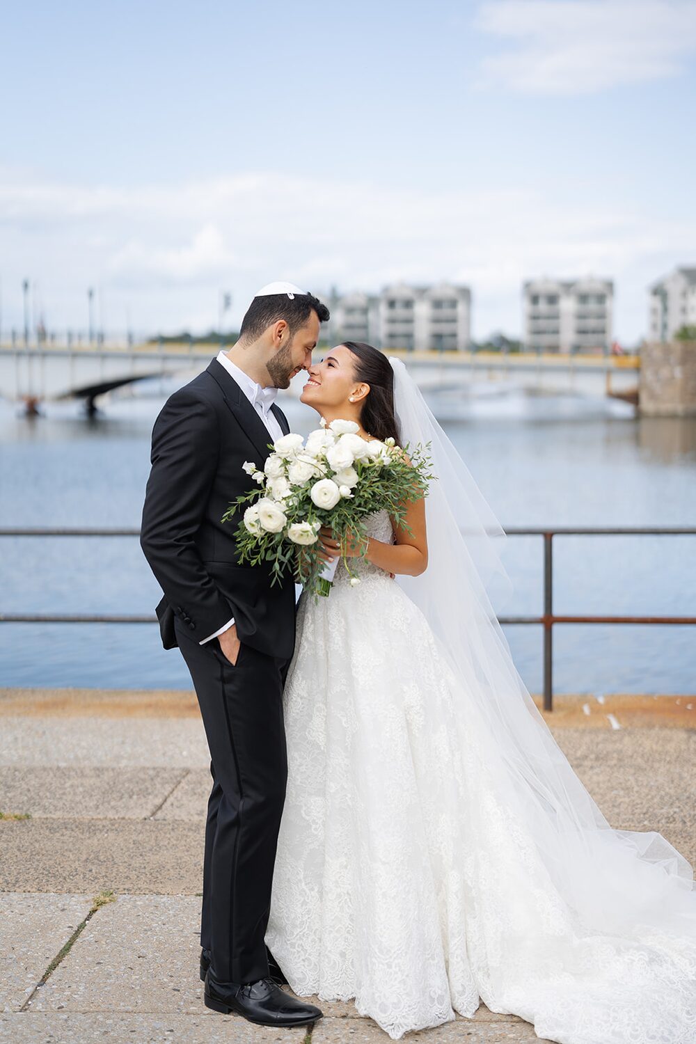 A kiss on the New Rochelle waterfront promenade with the marina and bridge behind.