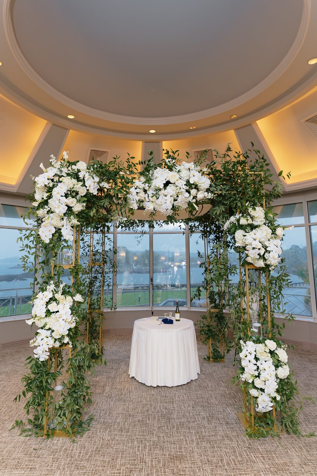 White floral chuppah in front of the windows at Glen Island Harbour Club