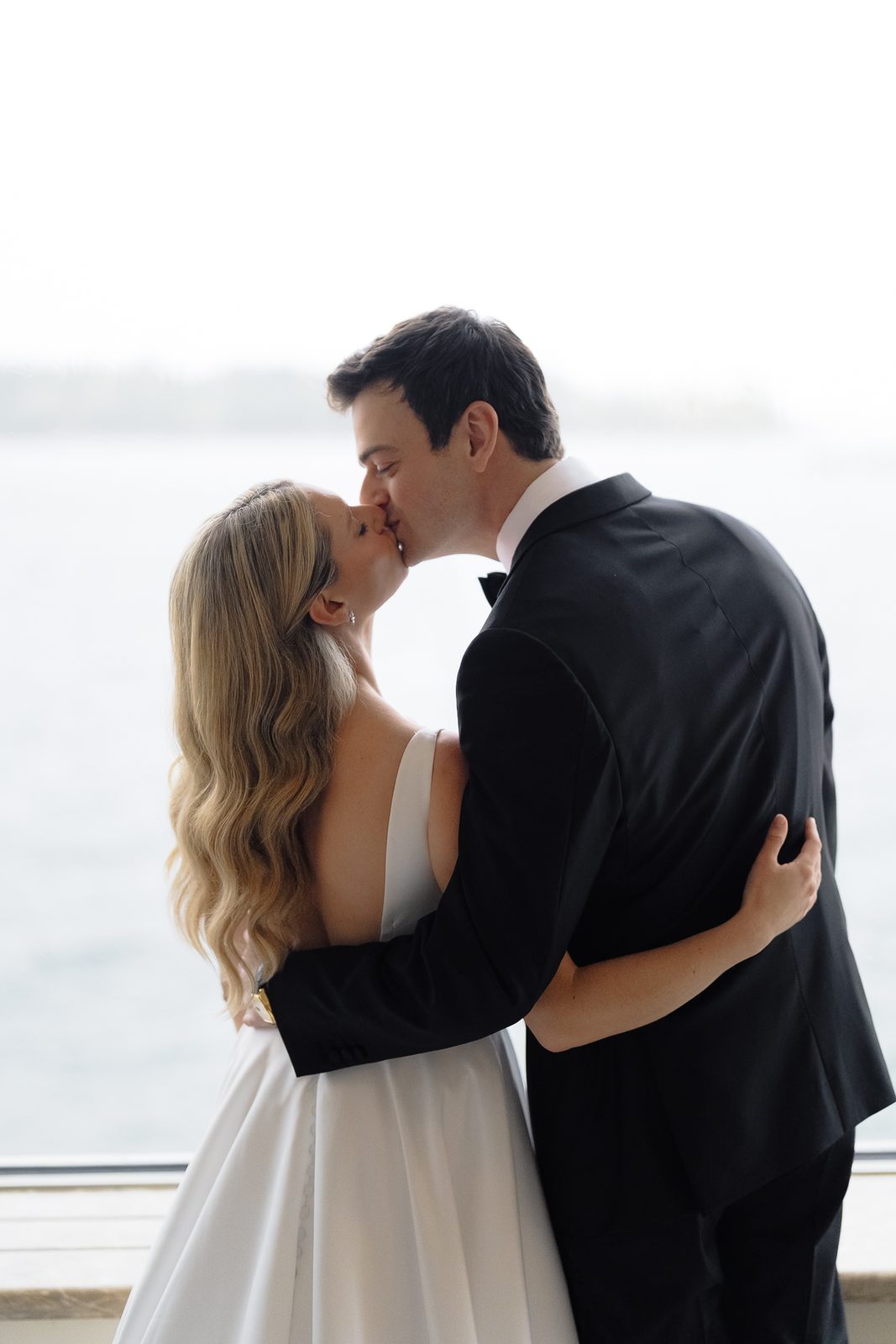 Hana and David kissing against the water light at Glen Island Harbour Club
