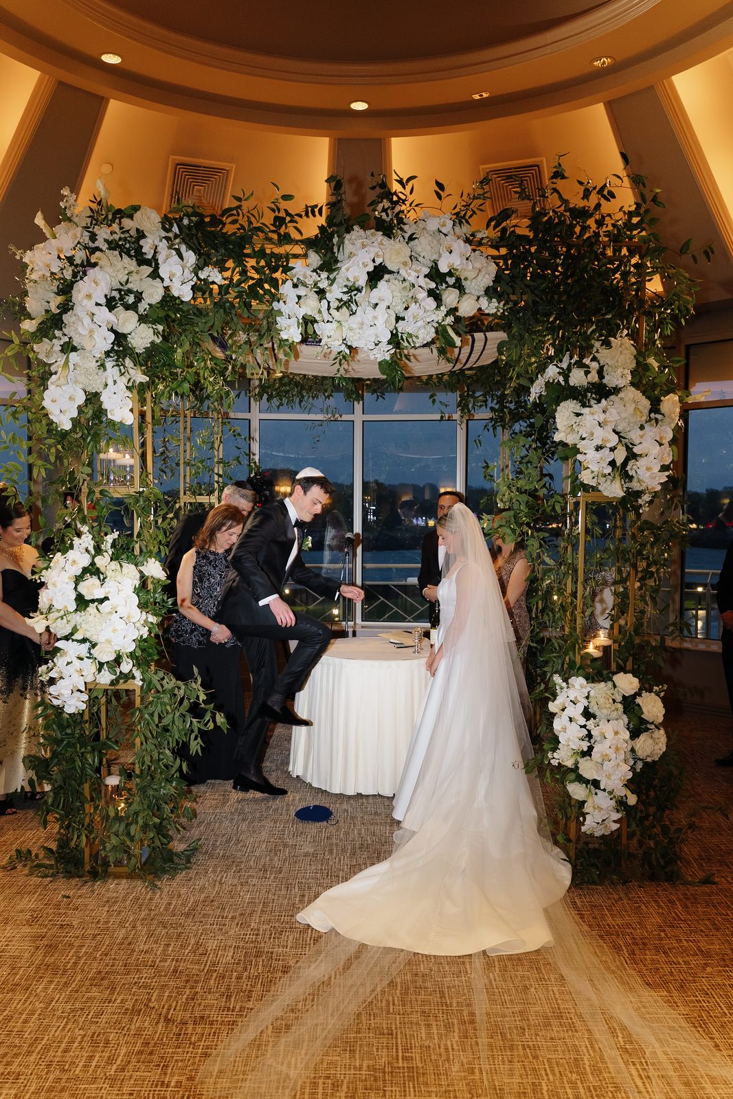 Hana and David under the white floral chuppah at Glen Island Harbour Club