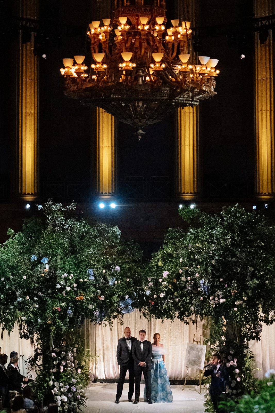 Gotham Hall's gilded columns and central chandelier framing the wedding ceremony