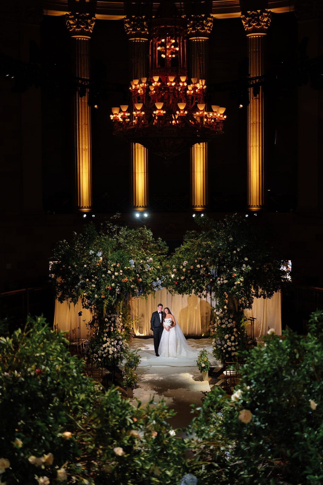 A greenery-and-floral chuppah standing between the Corinthian columns of Gotham Hall
