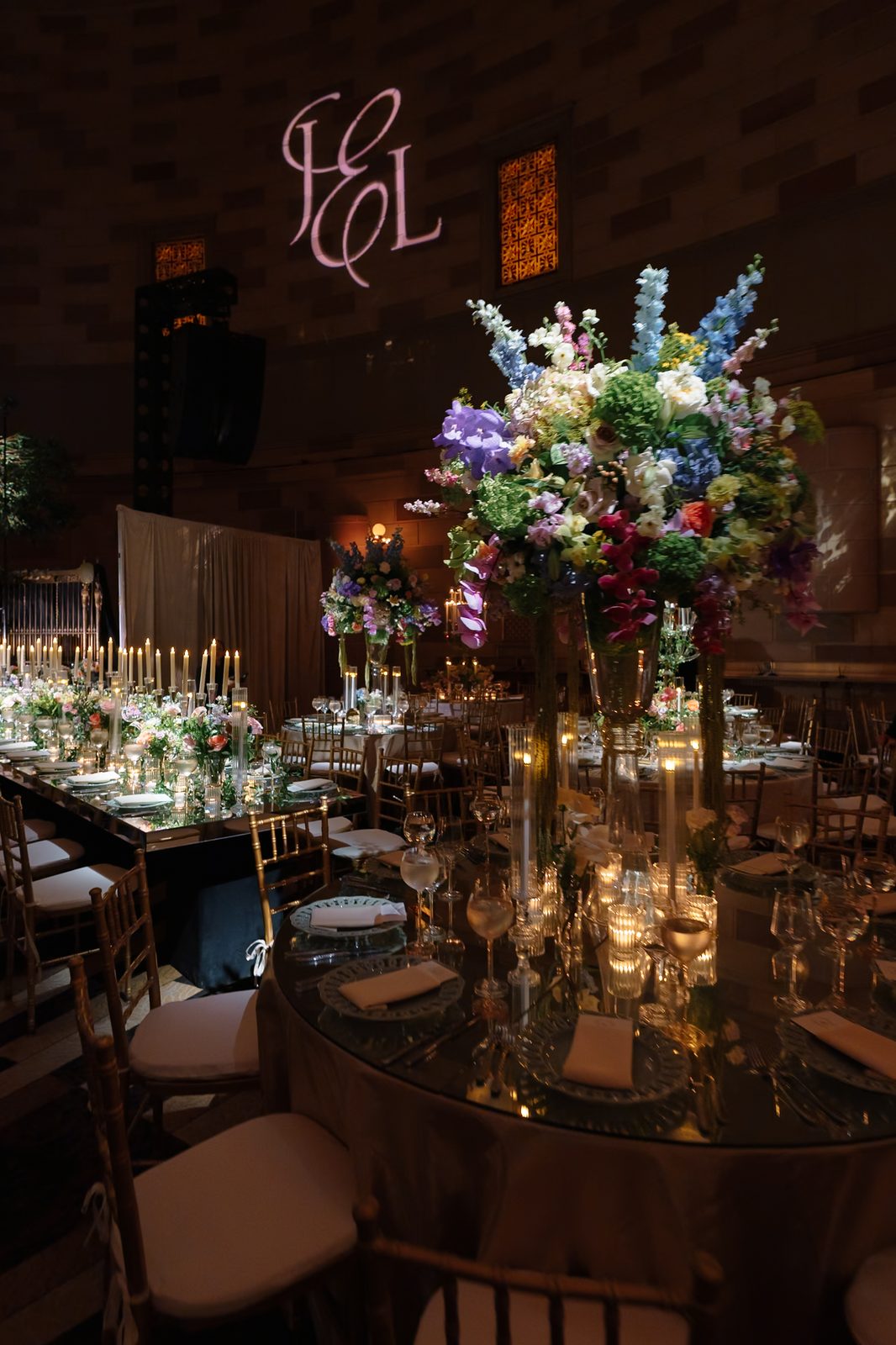 A Gotham Hall reception table with tall florals in blue and blush, set with gold candelabra