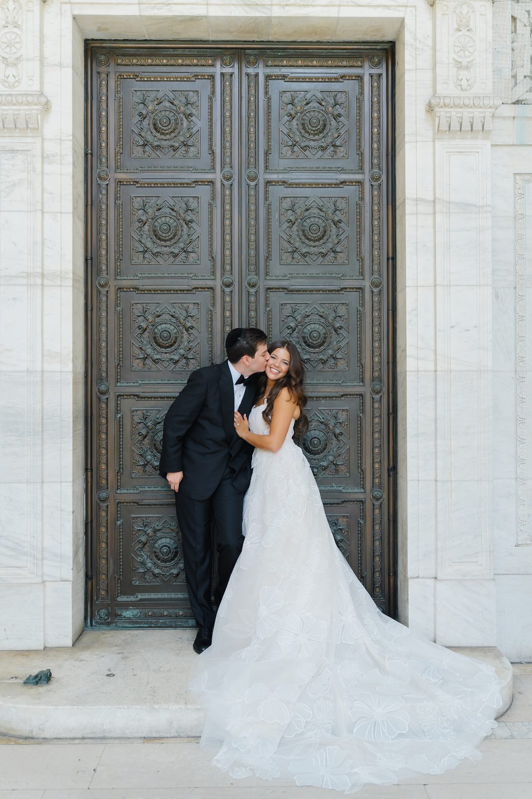 Jessie and Linus kiss against the bronze doors of the New York Public Library