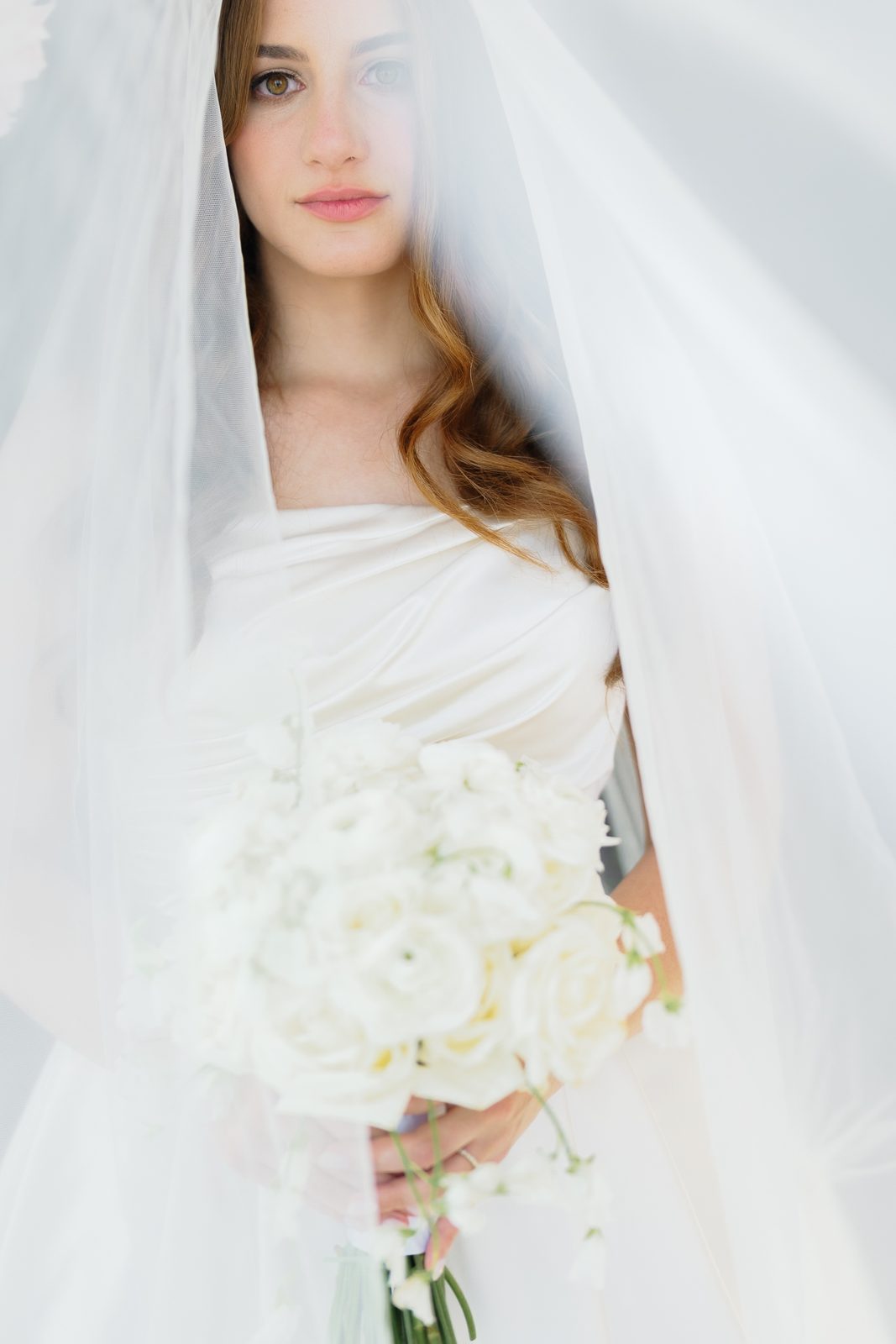 The veiled bride with her white bouquet