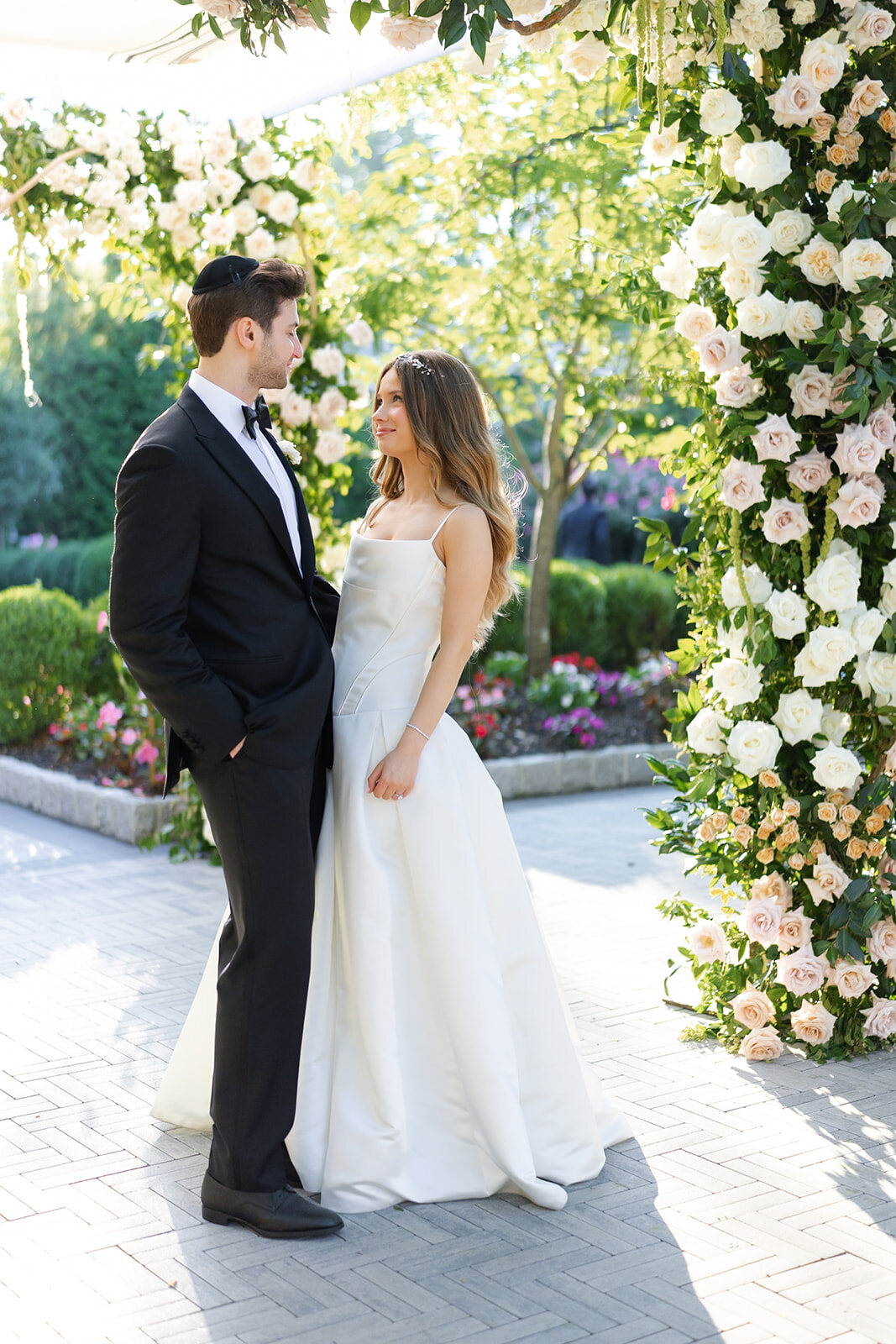 Noa and Nate beside the white rose arch in the garden