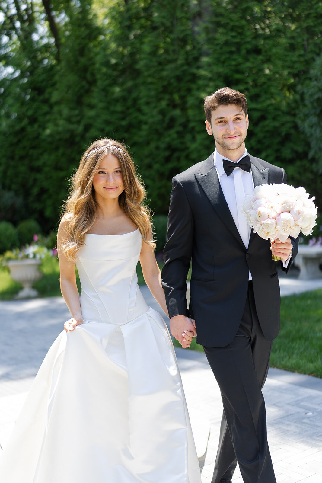 Noa and Nate walk hand in hand down the garden path