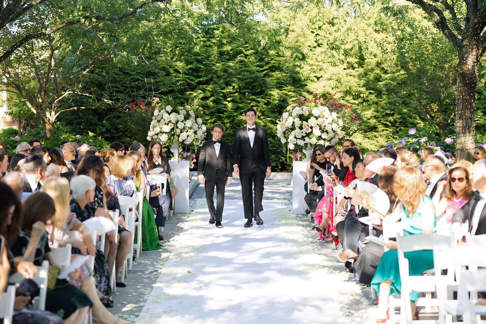 Guests line the garden aisle as the processional begins