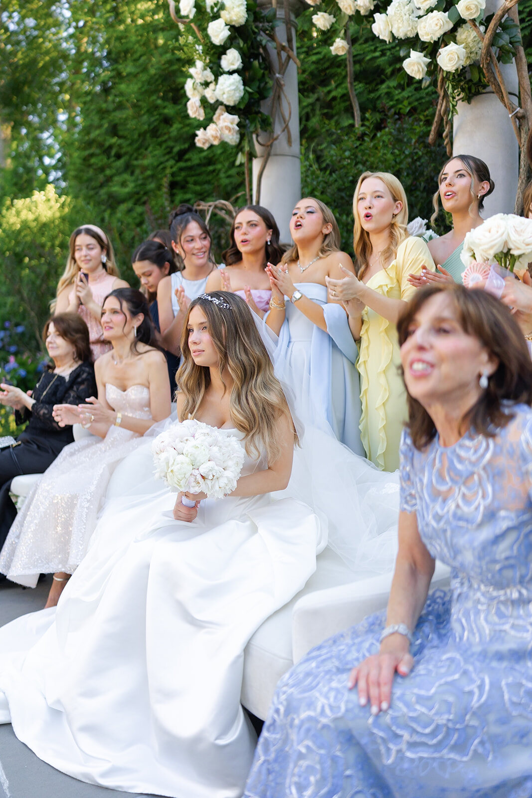 Noa on her chair at the kabbalat panim with her mother and bridesmaids beside her