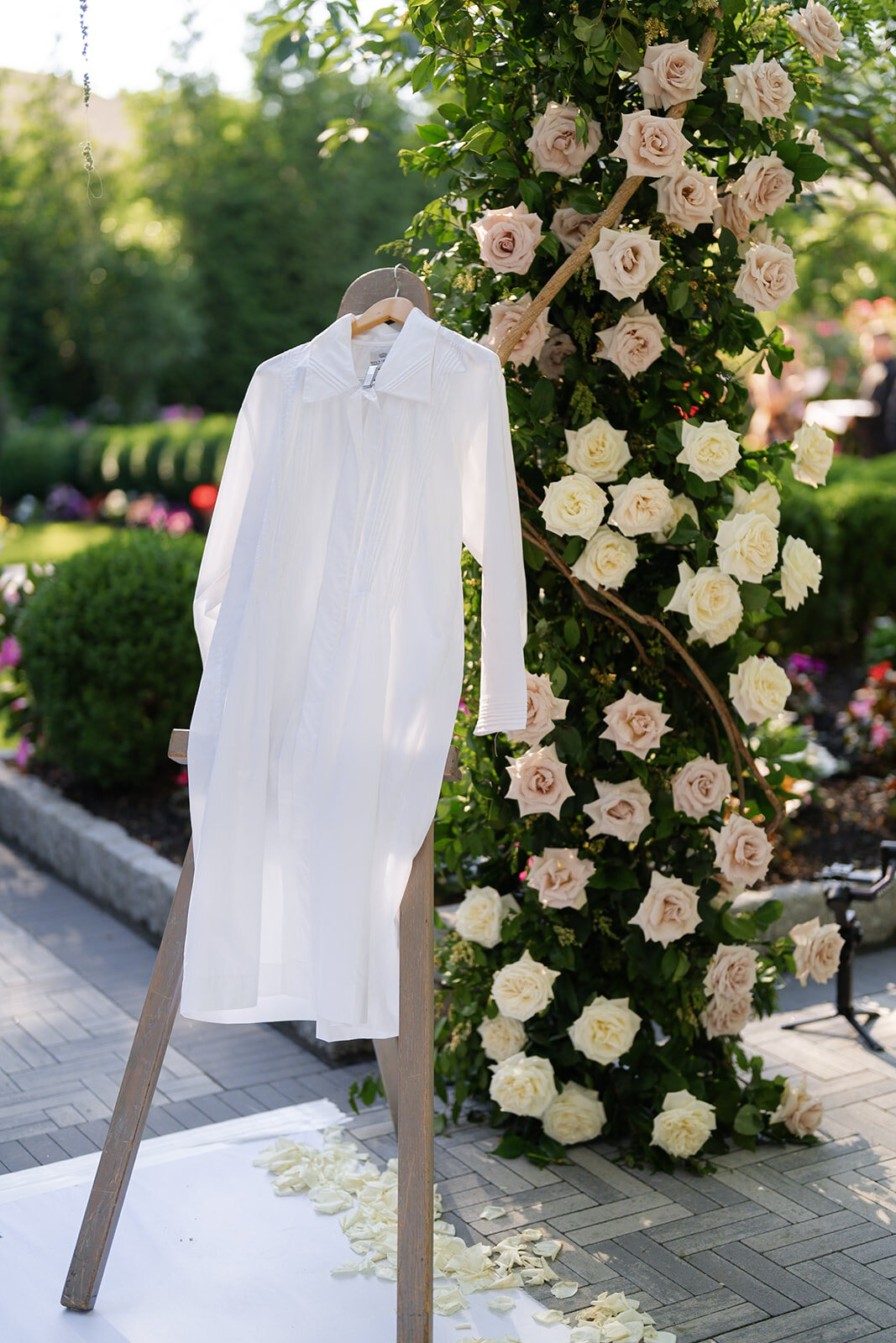 Nate’s kittel hangs beside a white rose floral arch in the garden