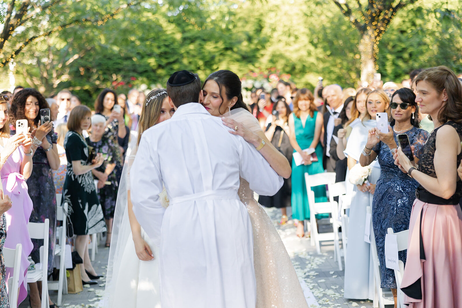 Nate in his white kittel embraces family in the aisle