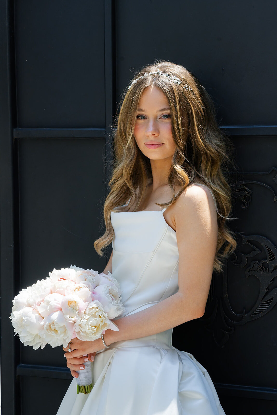 Noa with her peony bouquet against the black iron gate