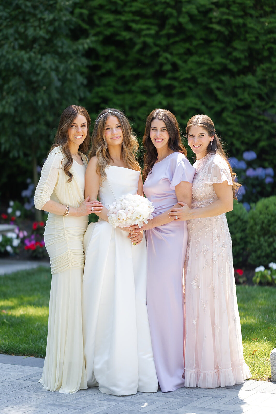 Noa with her bridesmaids in soft pastel gowns in the gardens