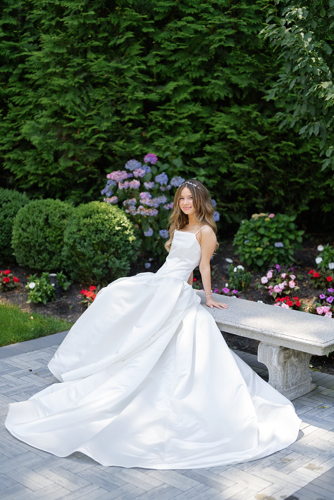 Noa in the gardens, the long train of her gown spread across the stone path