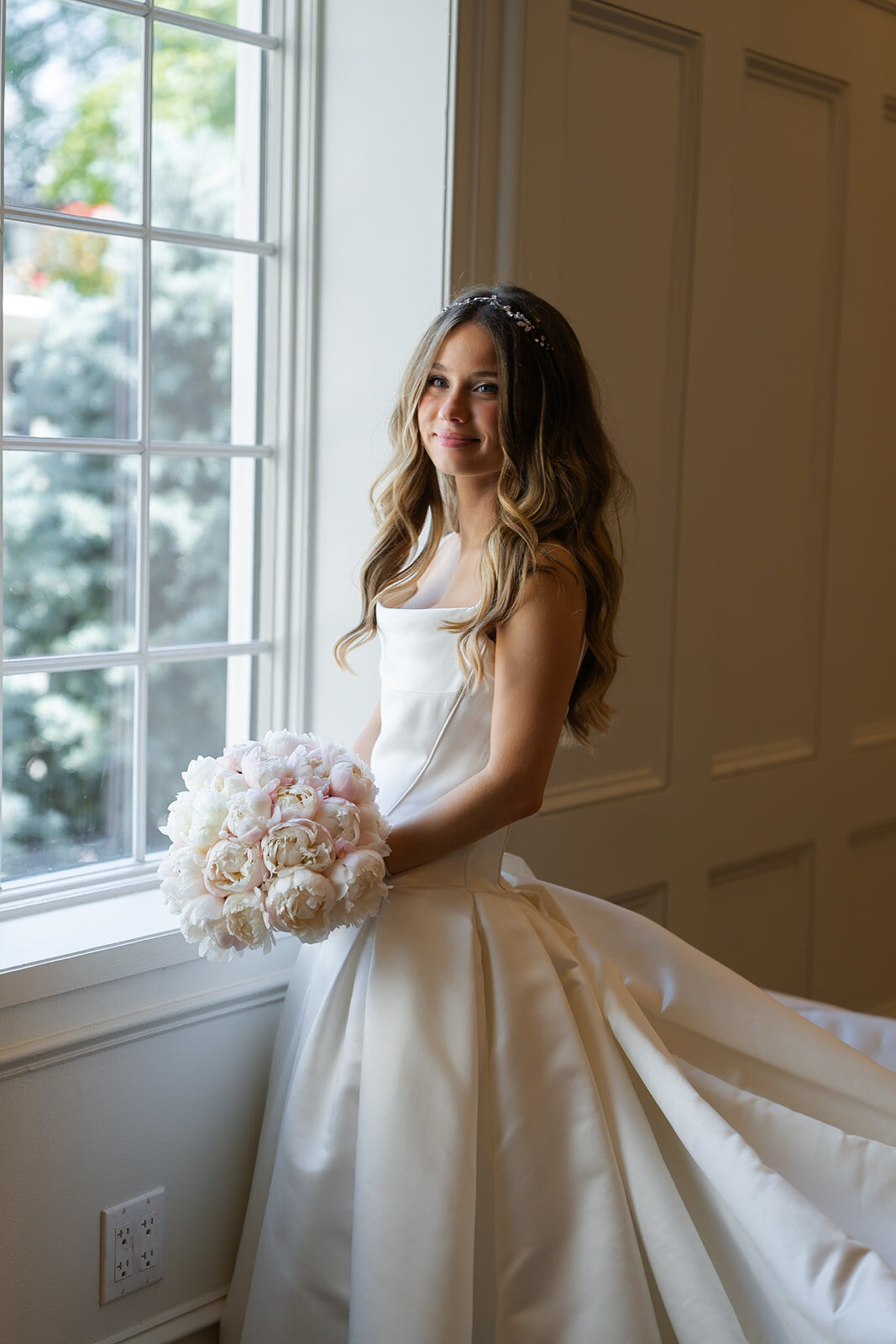 Noa in window light inside the estate, her gown pooled around her