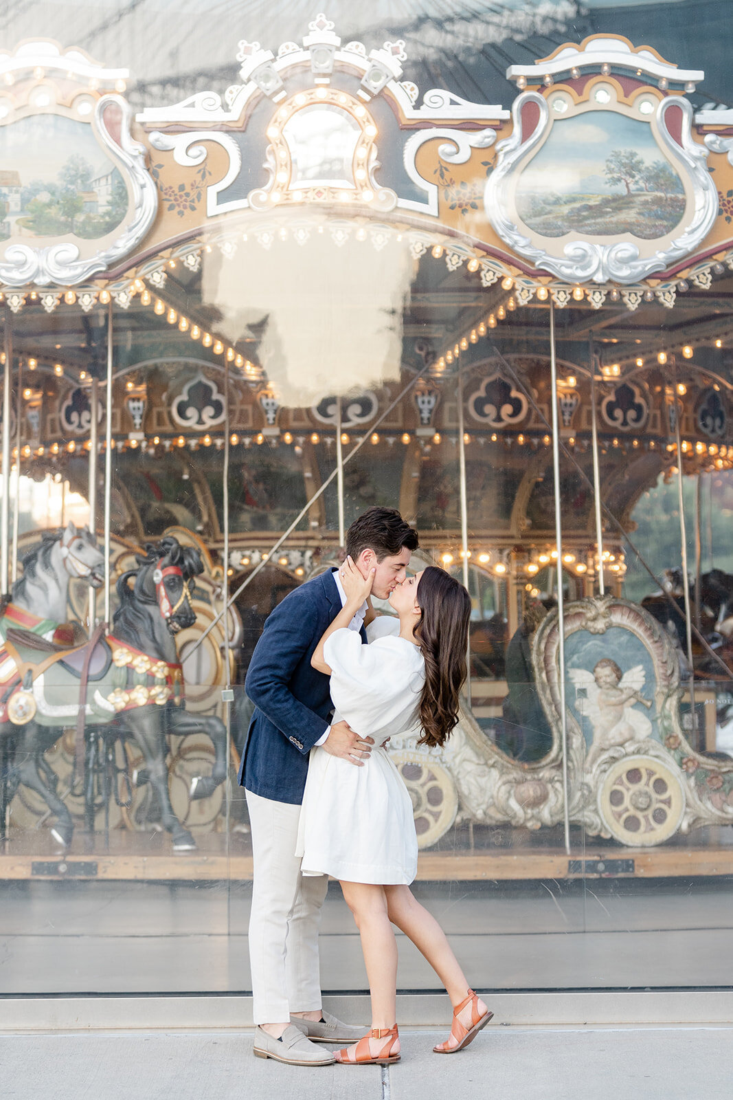 A couple in front of Jane's Carousel in DUMBO with the Brooklyn Bridge behind them.
