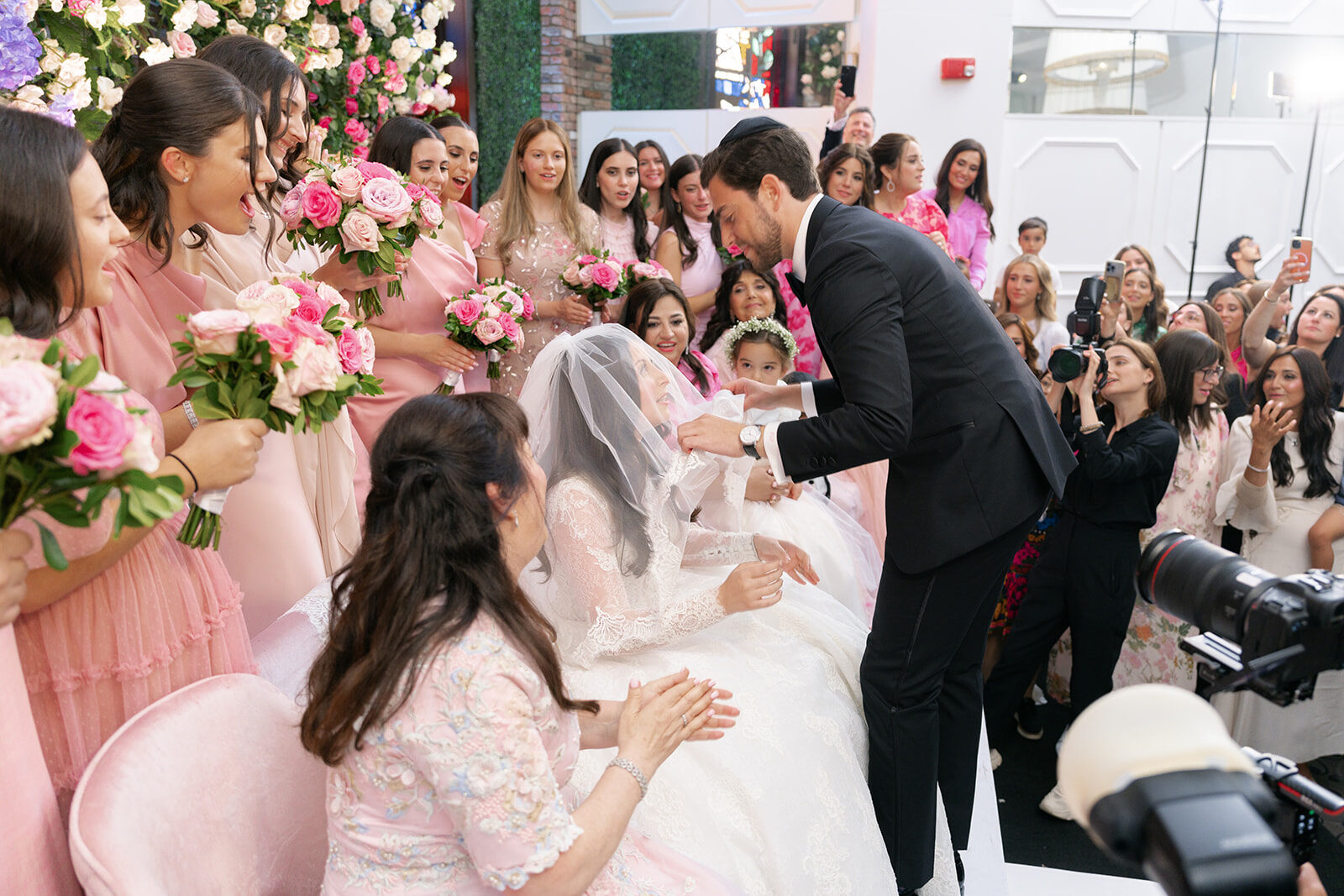 Aaron veils Arielle at the bedeken at Old Westbury Hebrew Congregation, bridesmaids in pink around her