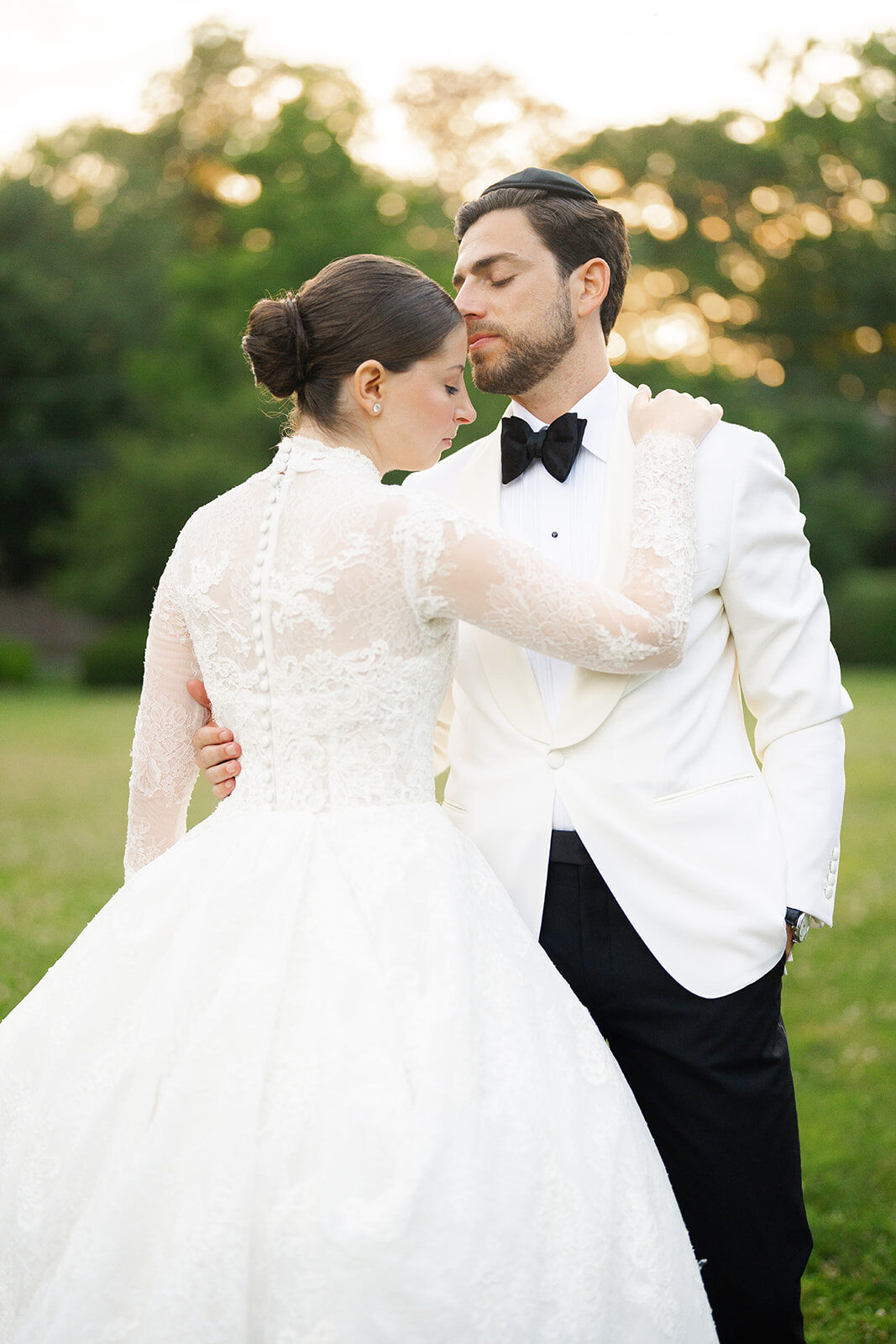 Arielle and Aaron in a white dinner jacket on the lawn at Old Westbury Hebrew Congregation at golden hour