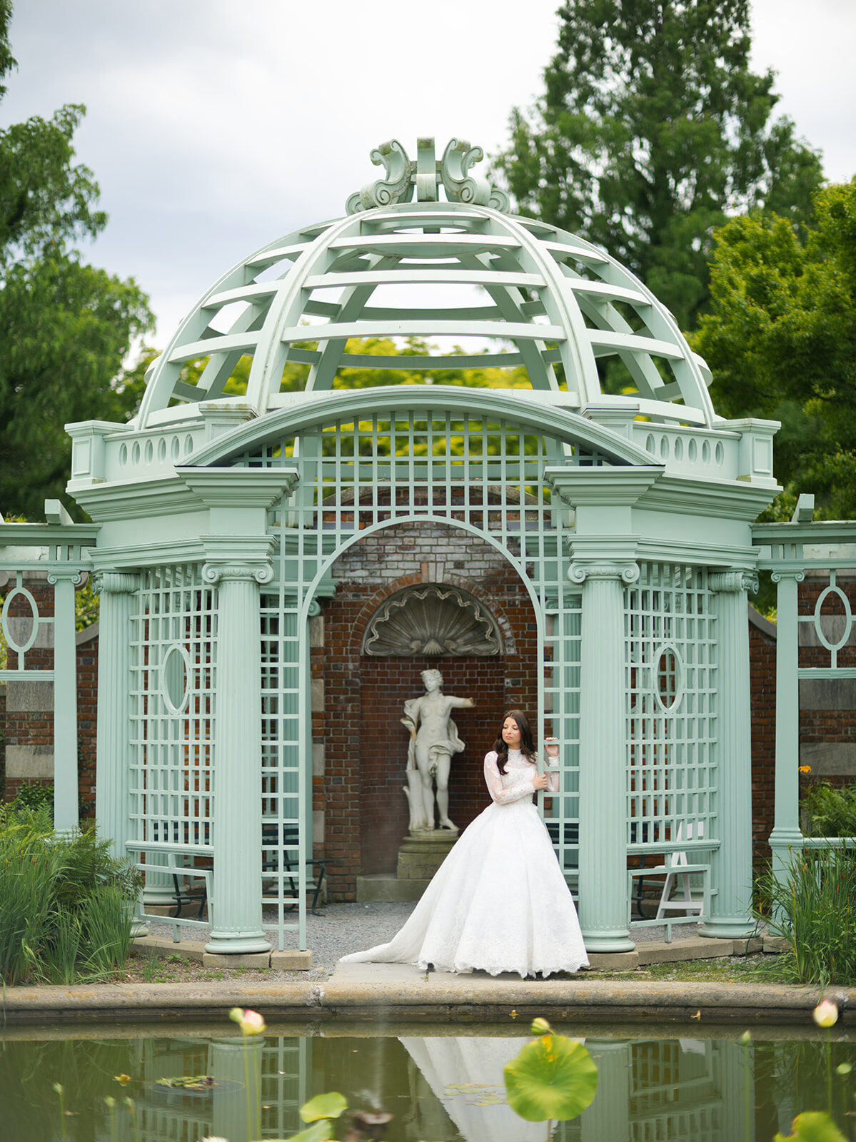 Arielle in a lattice garden gazebo over a lily pond during portraits near Old Westbury