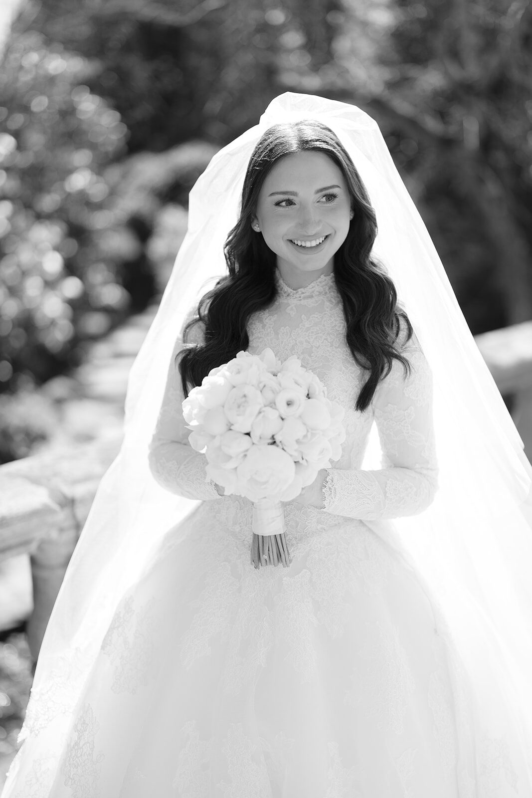 Kelly in her cathedral veil holding a white bouquet, portrait in black and white