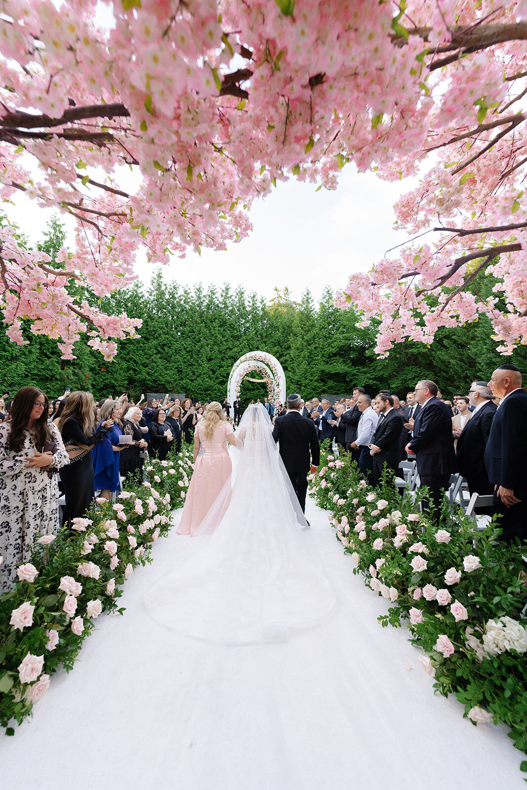 The outdoor ceremony aisle at Old Westbury Hebrew Congregation beneath a canopy of pink blossoms
