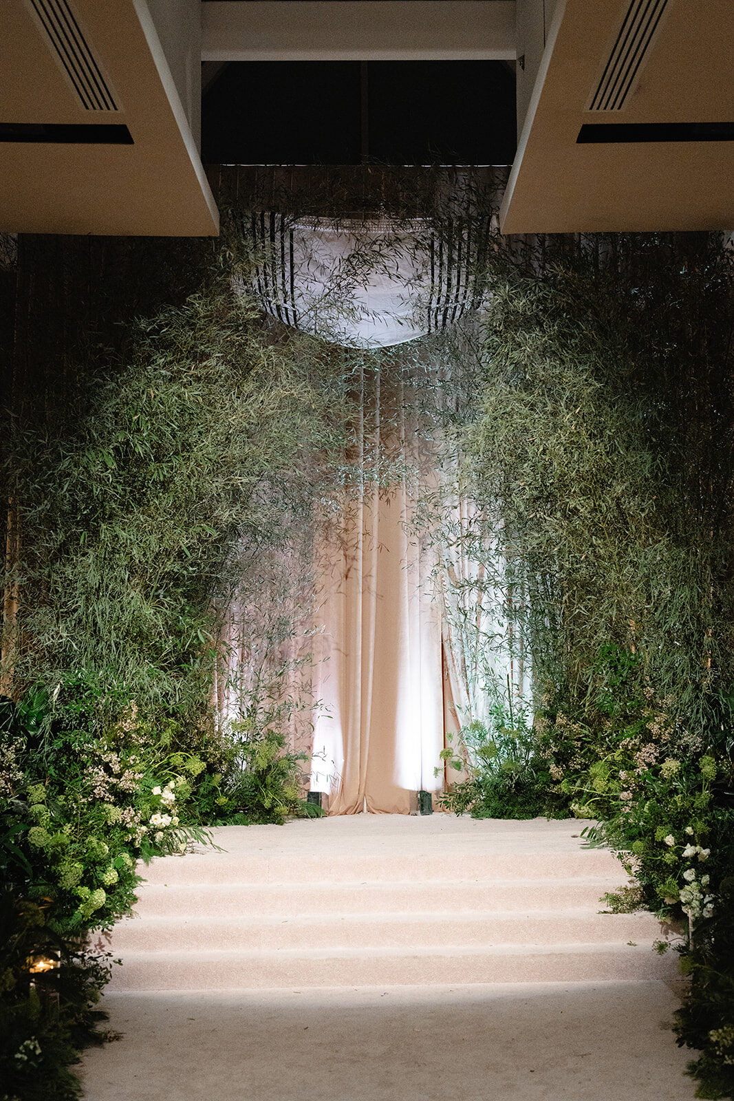The chuppah aisle at Old Westbury Hebrew Congregation set with living greenery walls and a lit archway