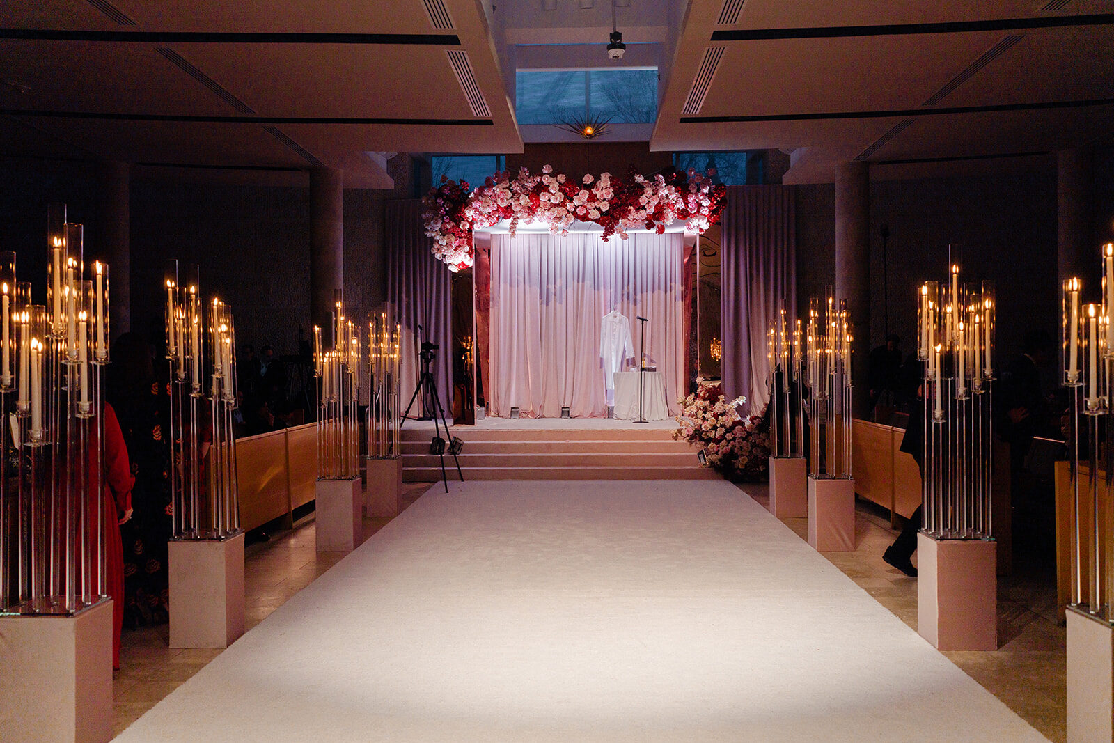 Candlelit chuppah of pink florals at the far end of the ballroom at Old Westbury Hebrew Congregation