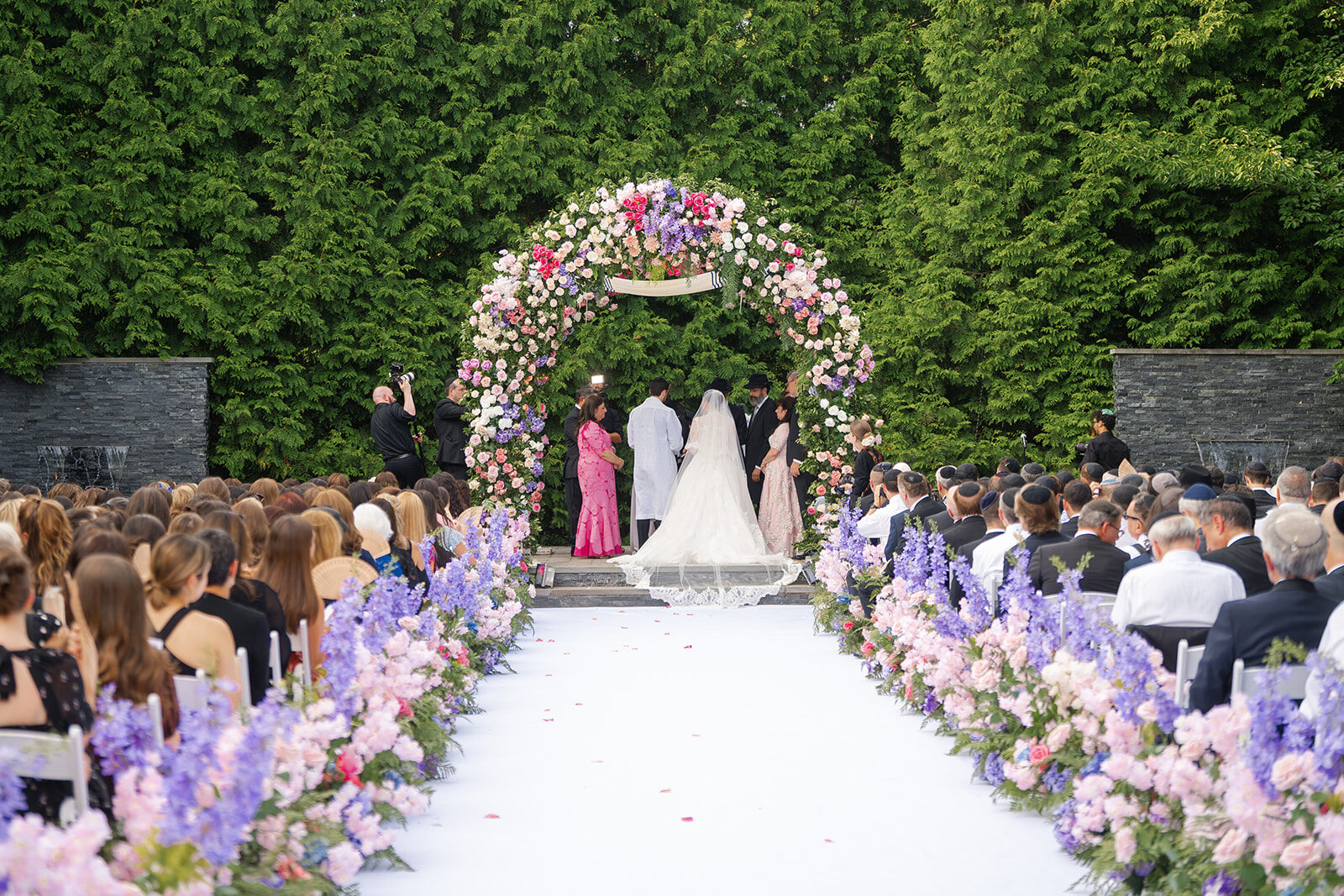 The outdoor chuppah at Old Westbury Hebrew Congregation, a floral arch against tall evergreens