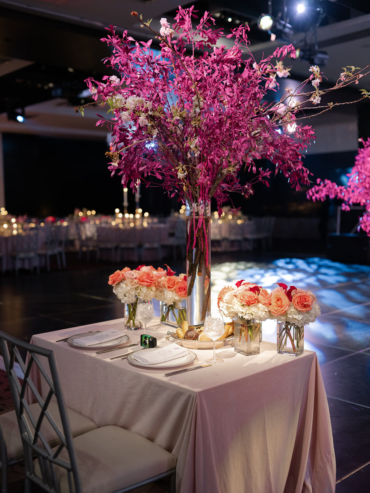 Reception table with a tall pink cherry blossom centerpiece at Old Westbury Hebrew Congregation