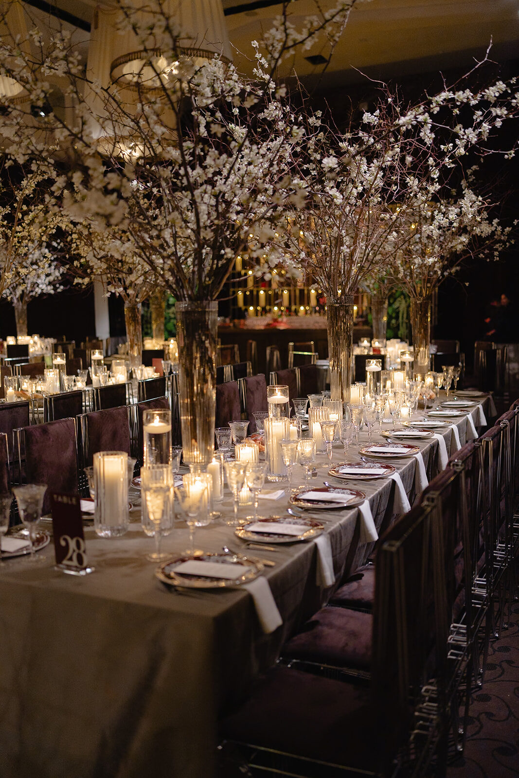 A long candlelit reception table with white branches at Old Westbury Hebrew Congregation
