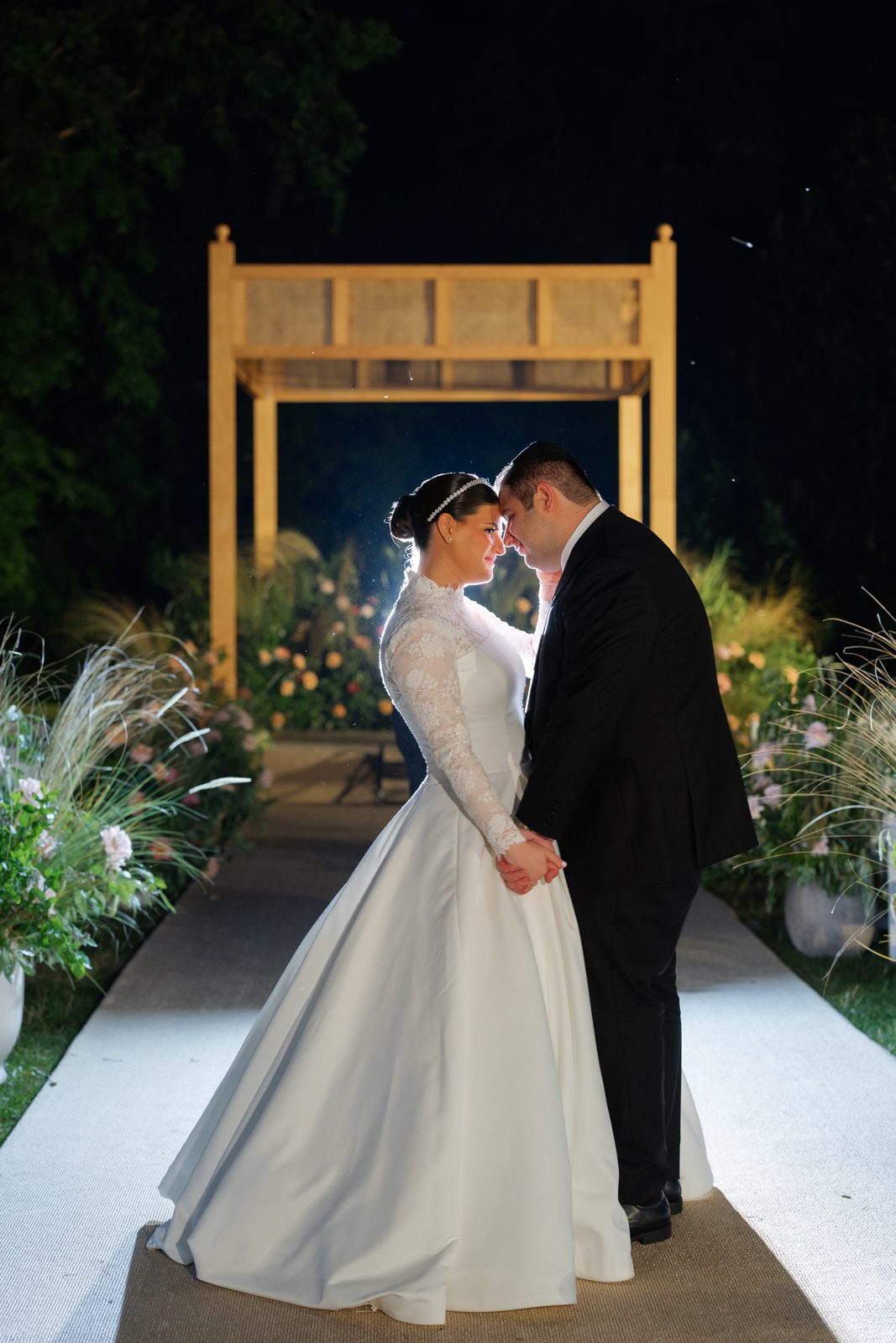 The couple under the lit chuppah at night