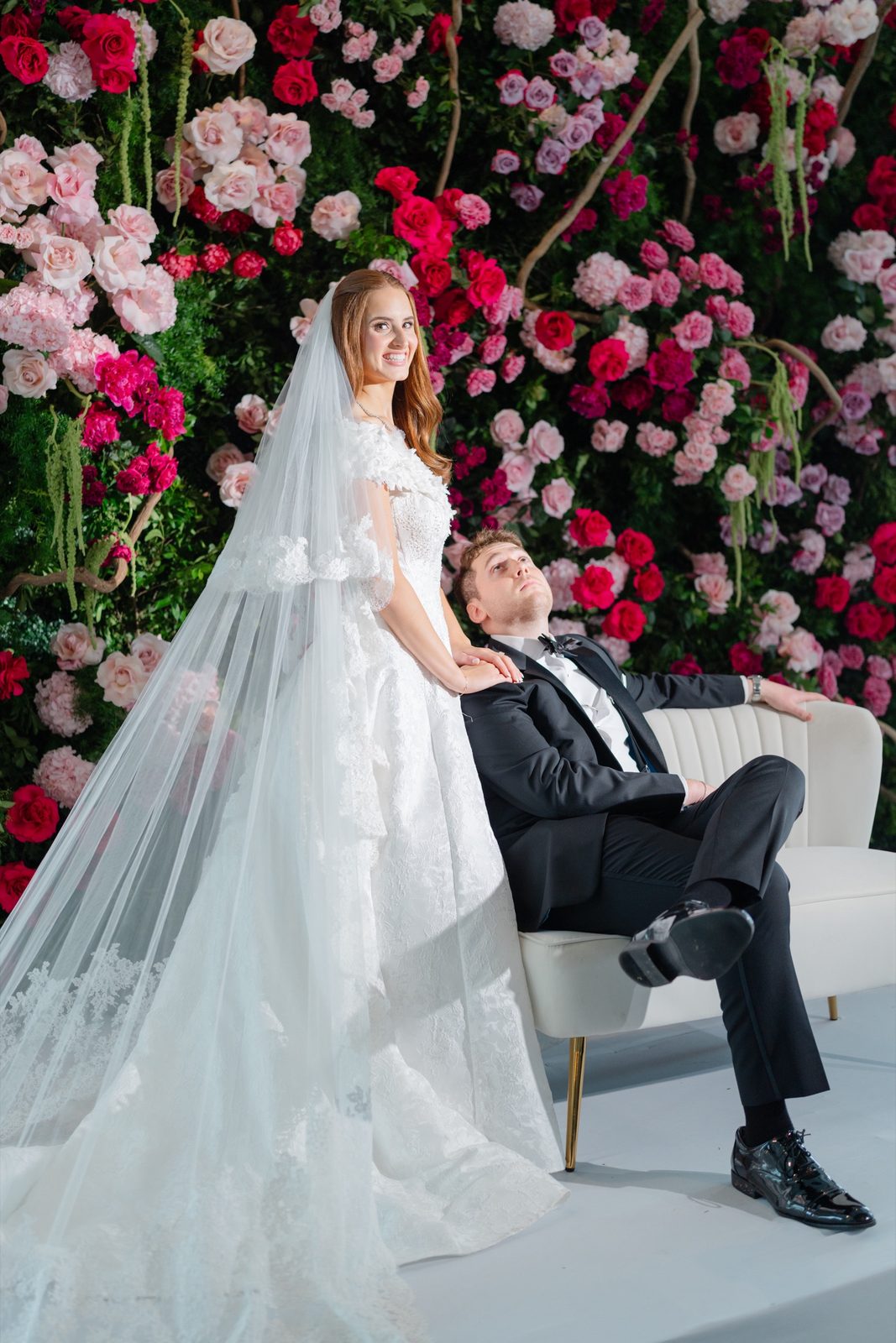 Olivia and Jeremy in front of a wall of pink and red roses