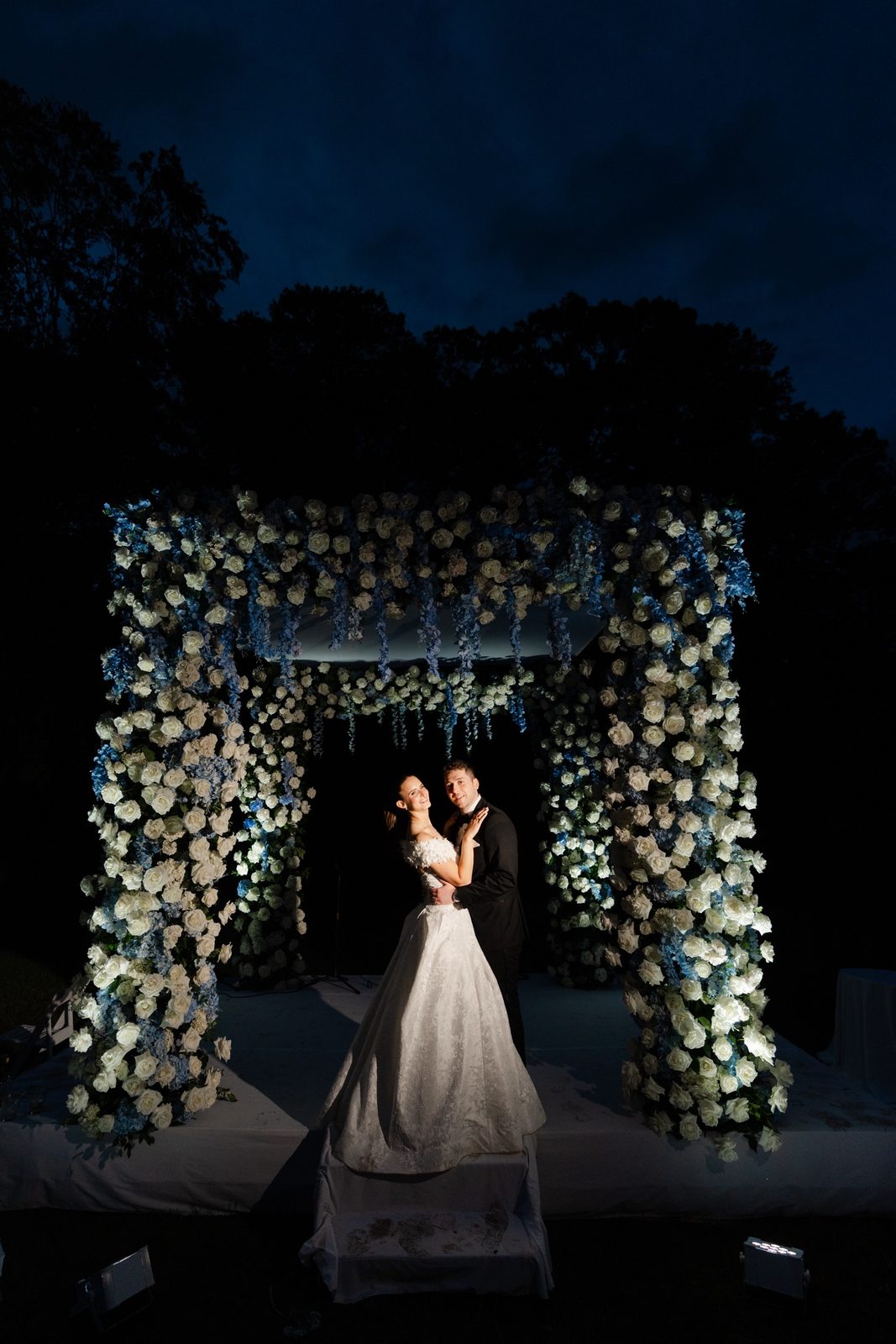 The chuppah lit up on the lawn after dark