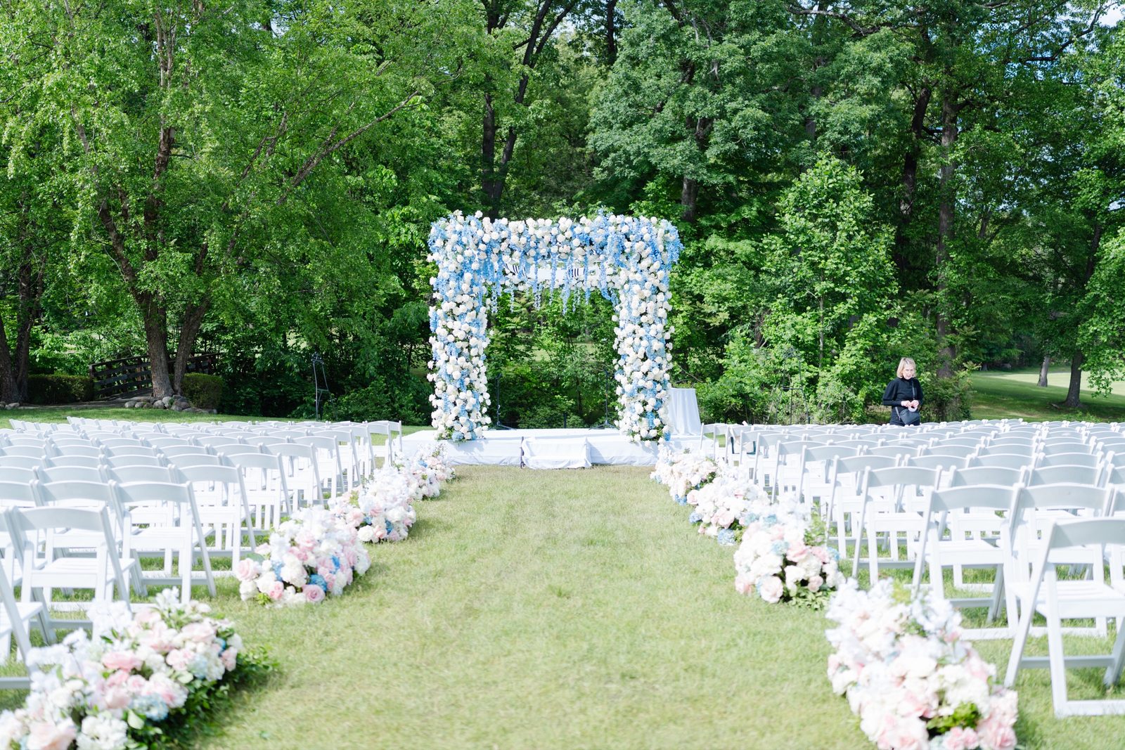 The ceremony set on the lawn with a blue and white floral chuppah