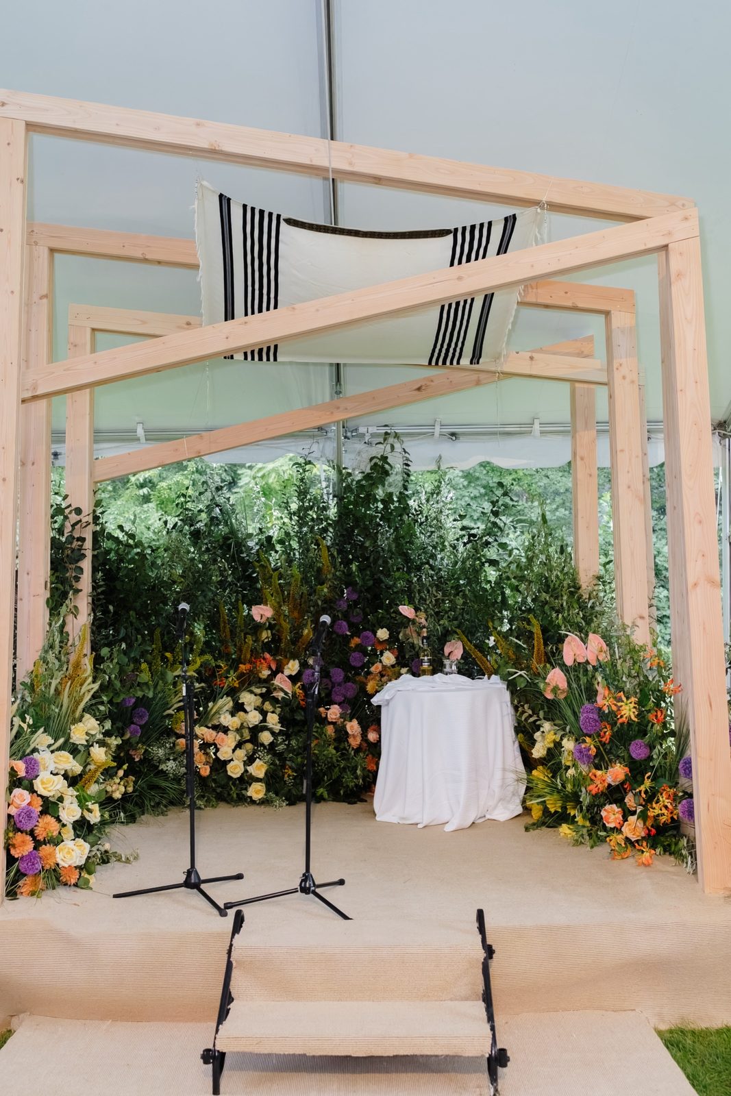 The wooden chuppah under the tent, dressed in greenery