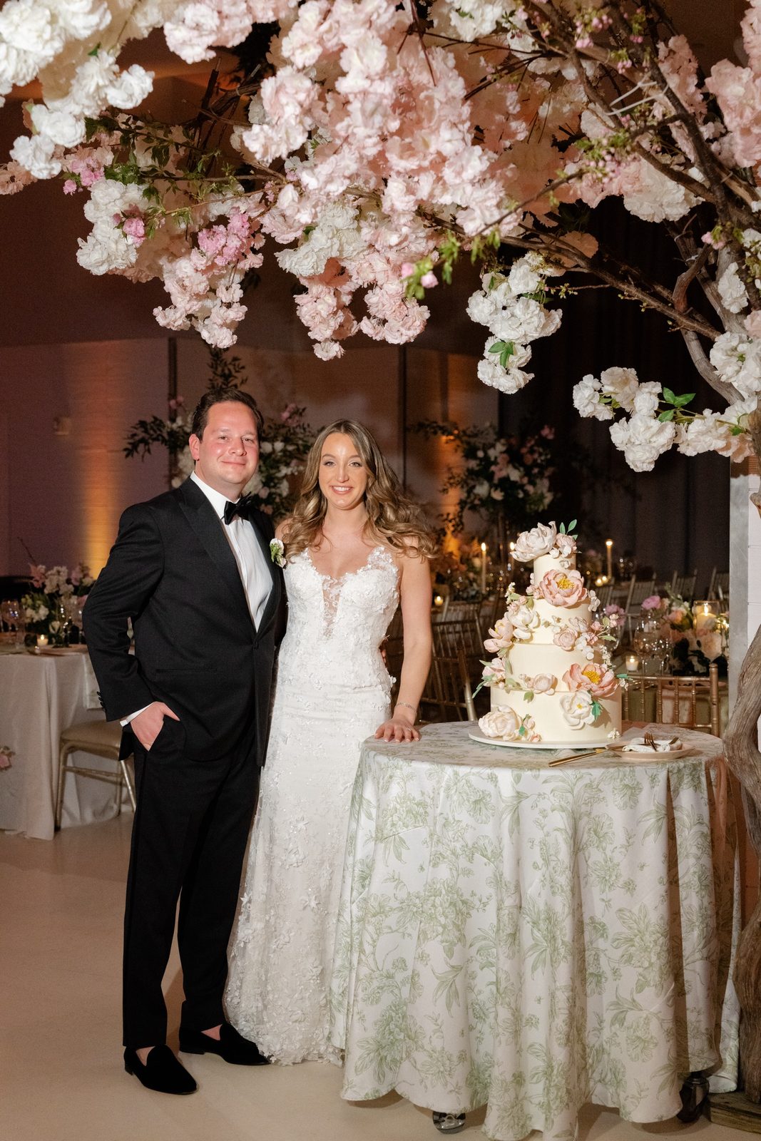 Amanda and Greg by the cake under the cherry blossom trees