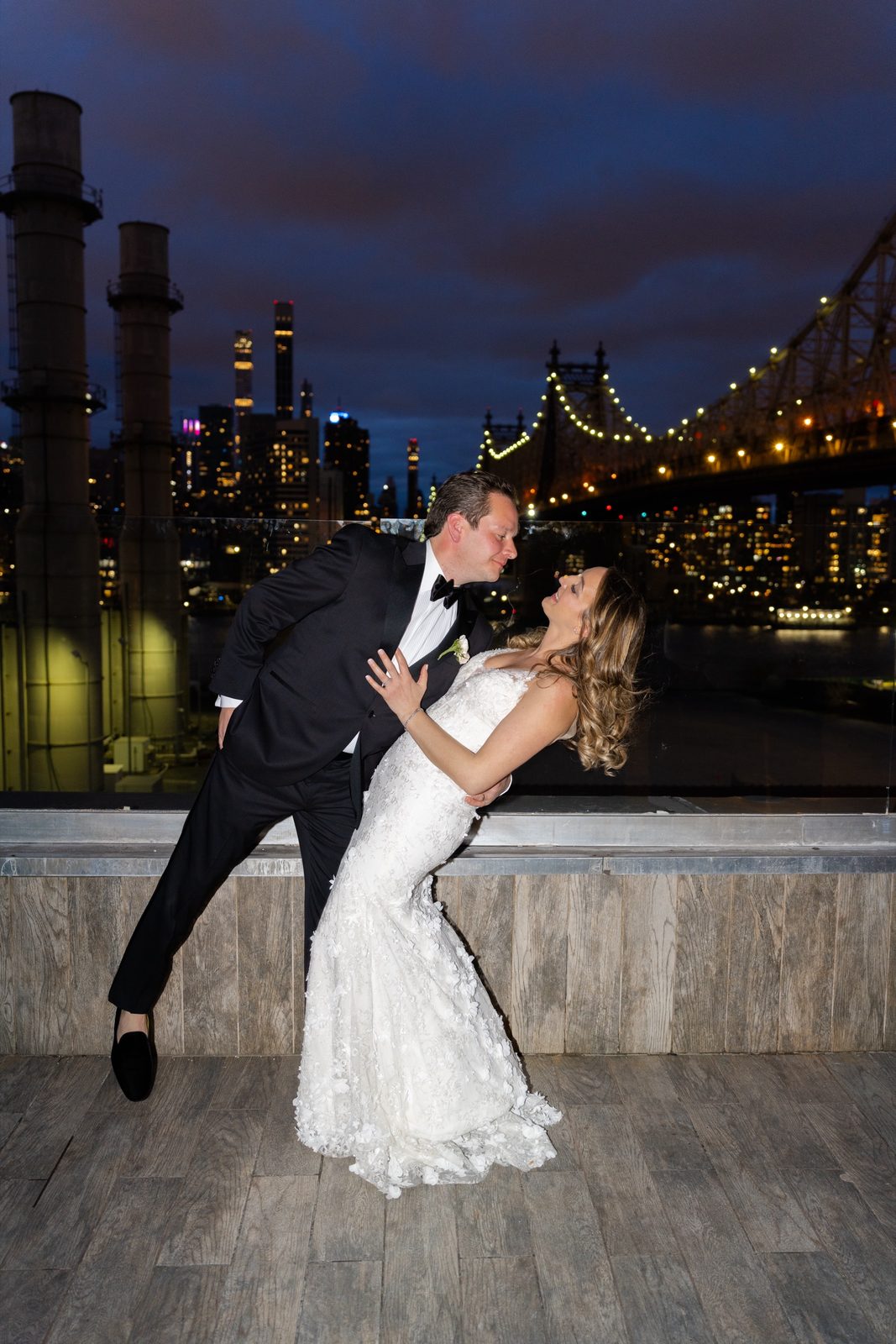 Greg dipping Amanda on the terrace at dusk with the Queensboro Bridge lit behind them