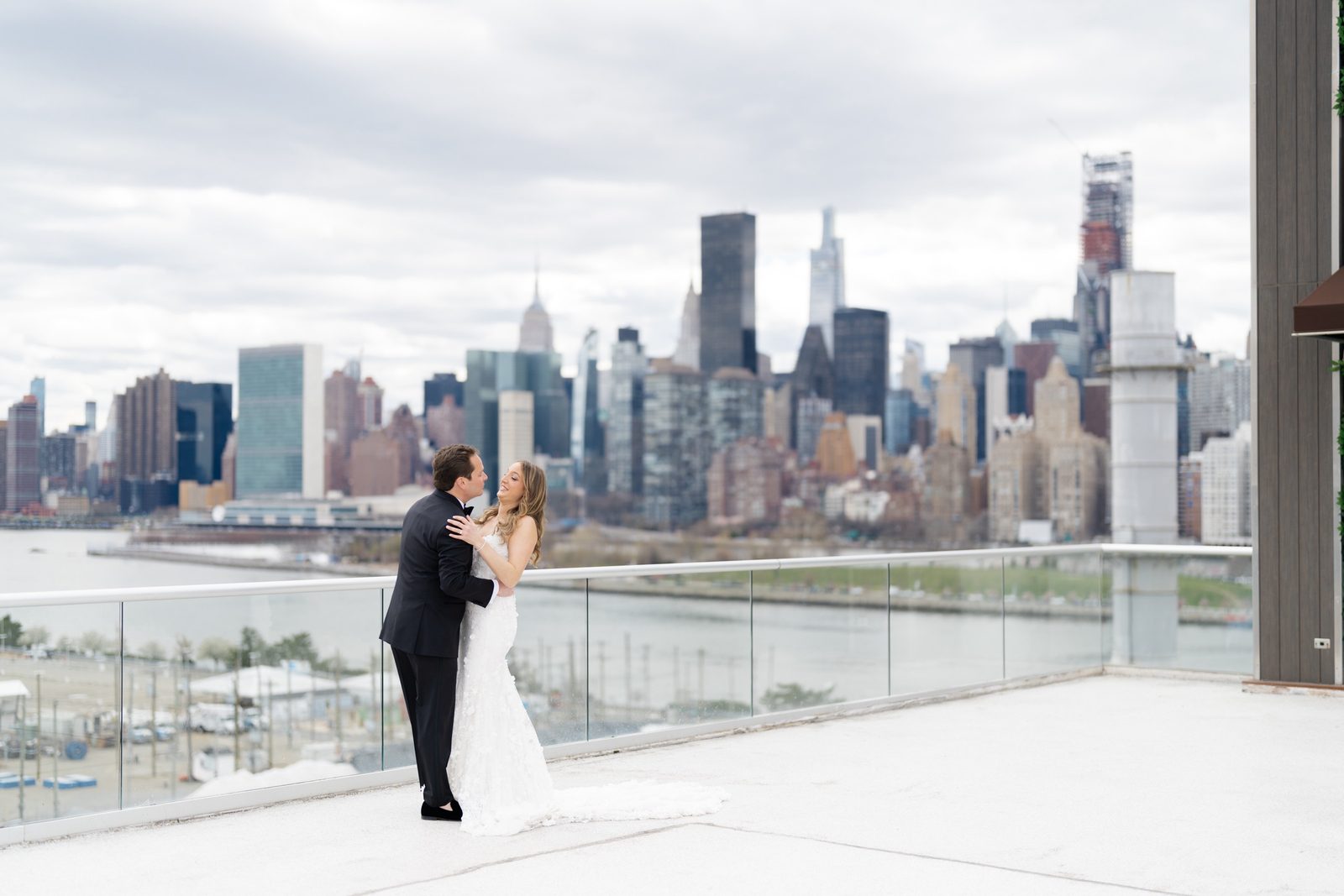 Amanda and Greg embracing on the rooftop above Long Island City