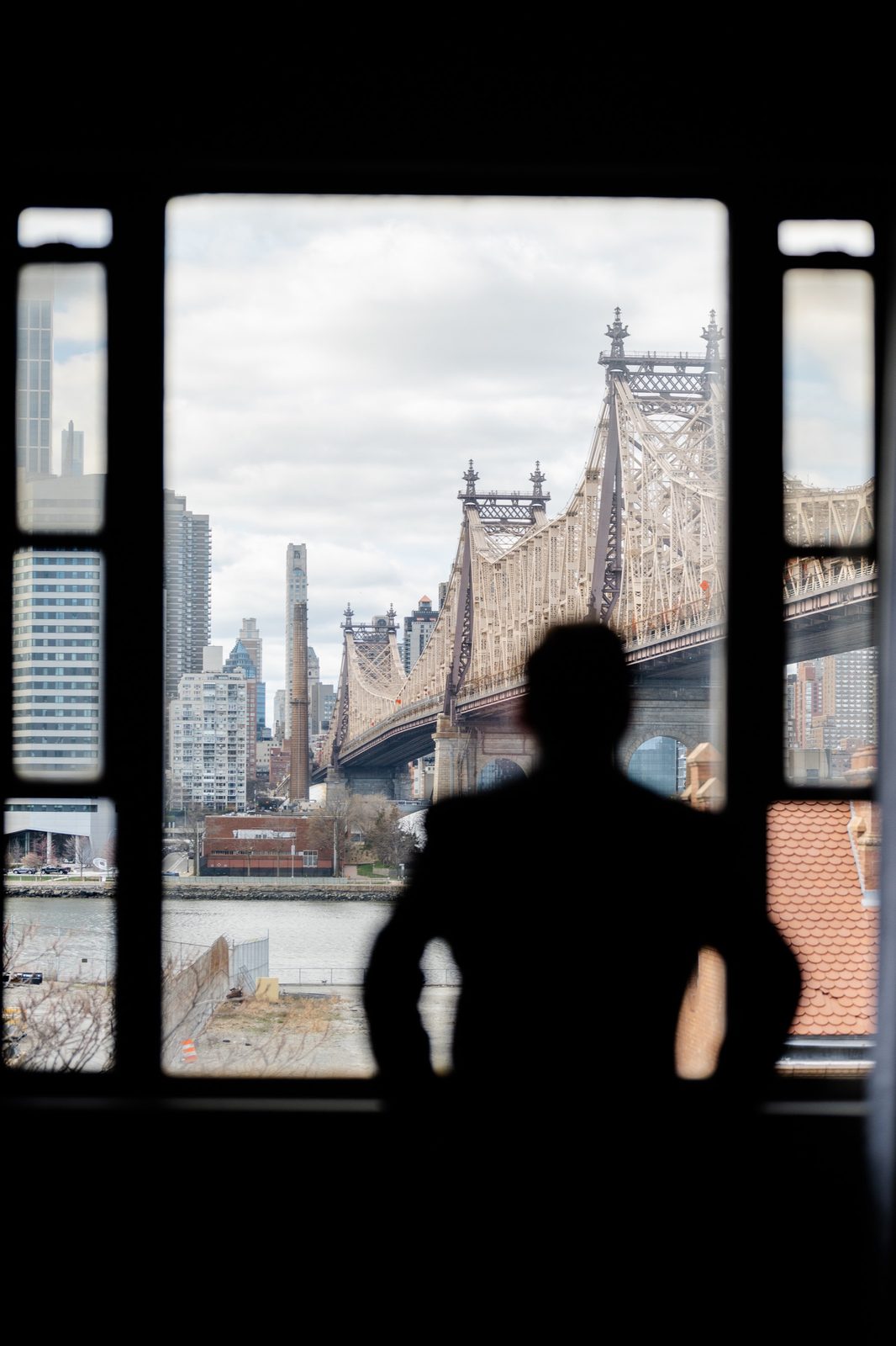 Greg in silhouette at a window framing the Queensboro Bridge