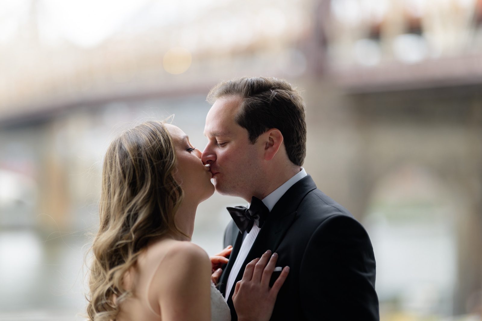 A kiss with the bridge soft behind them