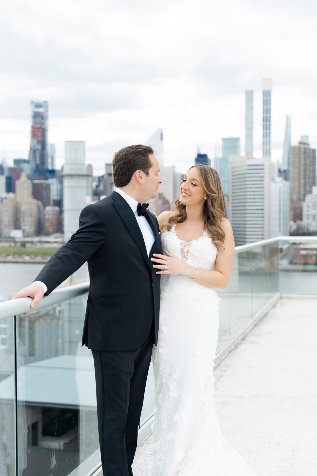 Amanda and Greg at the glass railing with the skyline behind them