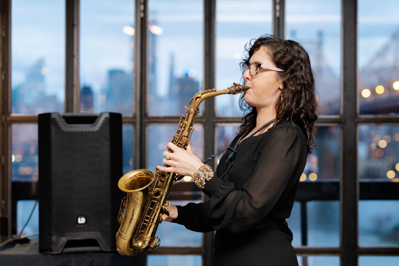 A saxophonist playing with the skyline behind her at cocktail hour