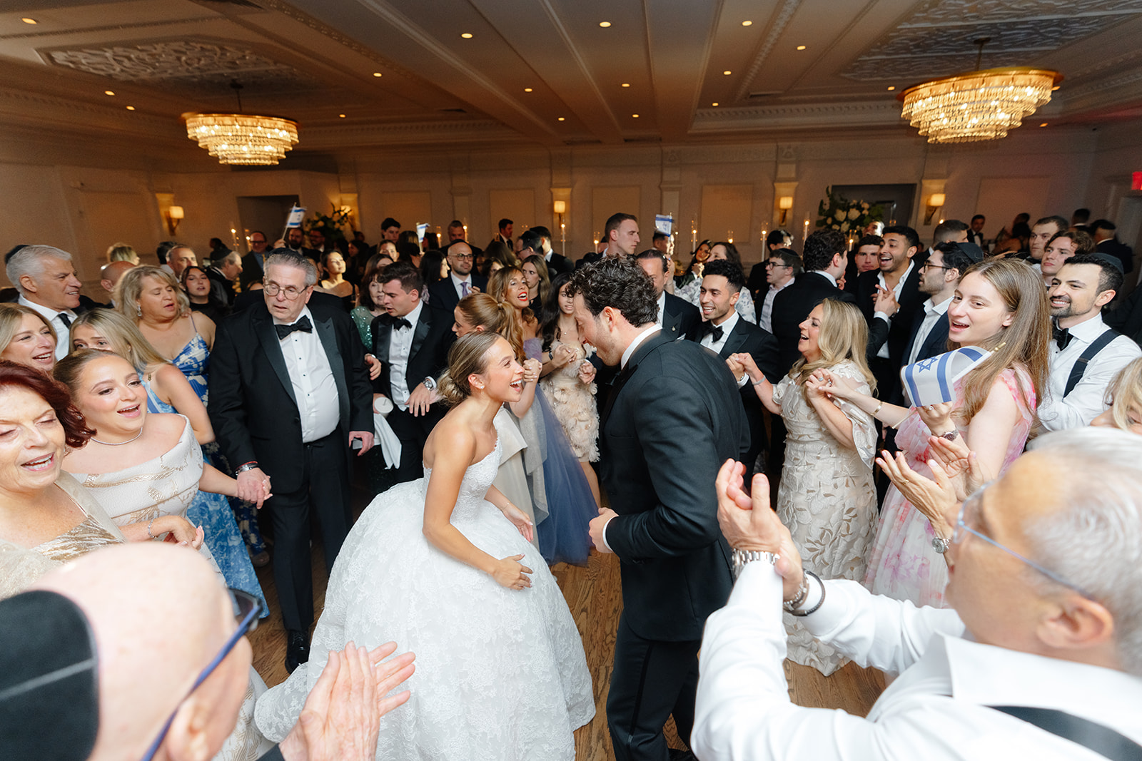 The hora in full swing under tiered chandeliers, Rebecca and Phil at the center of the circle