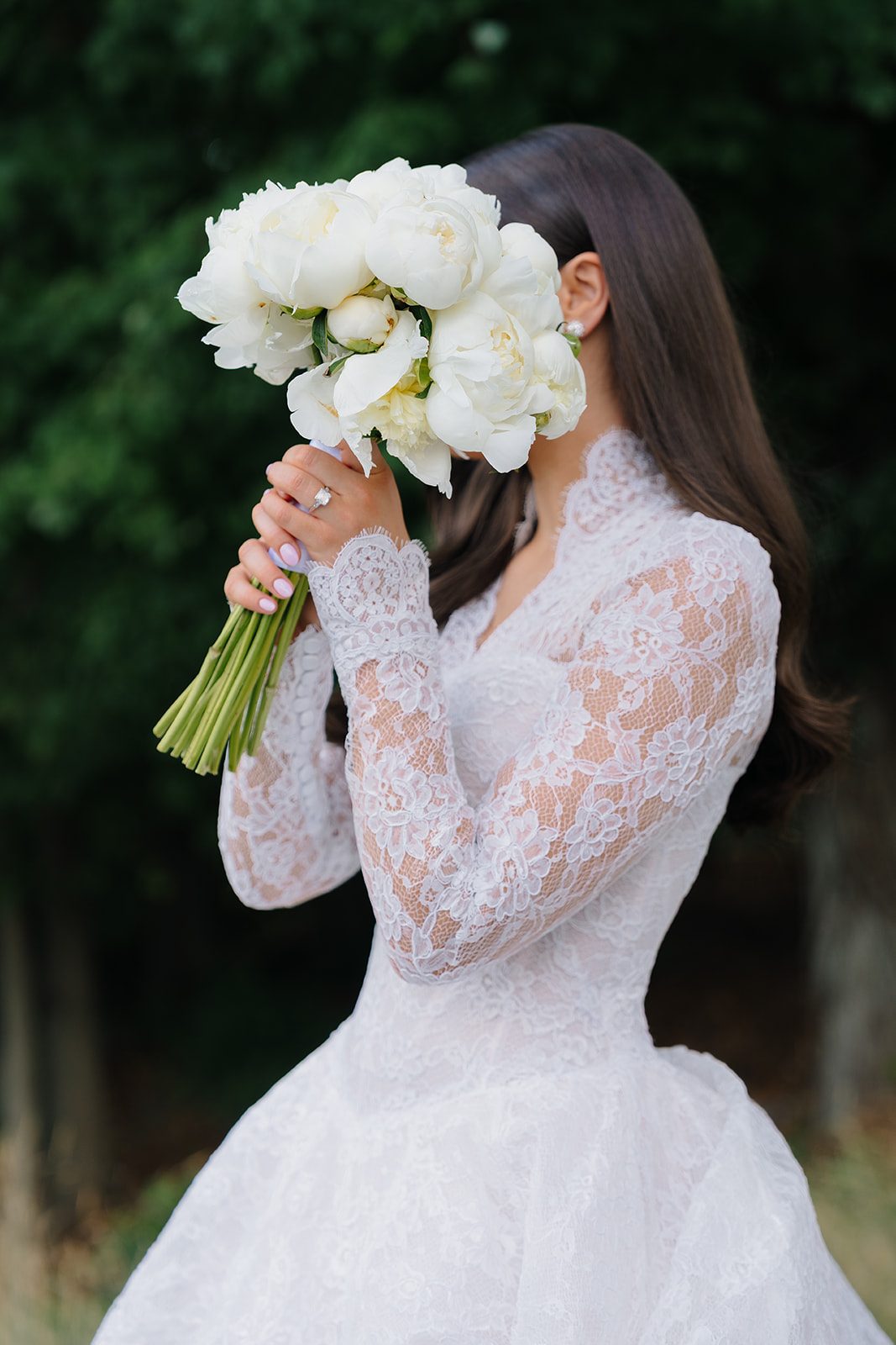 Bride playfully hiding behind her white peony bouquet