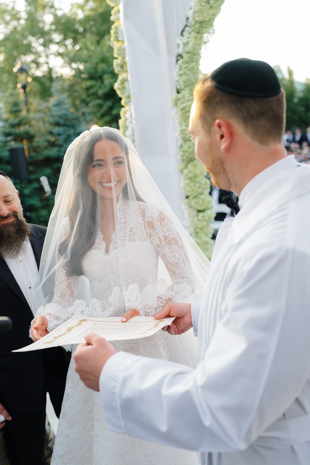 Rosalie smiling during the ketubah reading under the chuppah