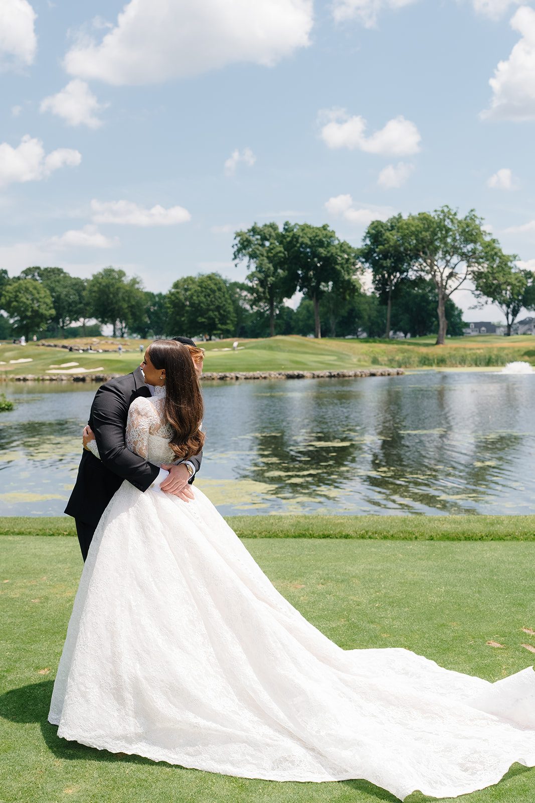 Bride and groom embracing at the water&rsquo;s edge at Edgewood Country Club